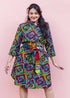 The model is wearing geometric print with rainbow colored dress paired with patchwork belt