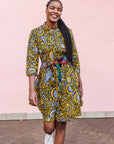 The model is wearing black dress with white and yellow botanical print paired with patchwork belt