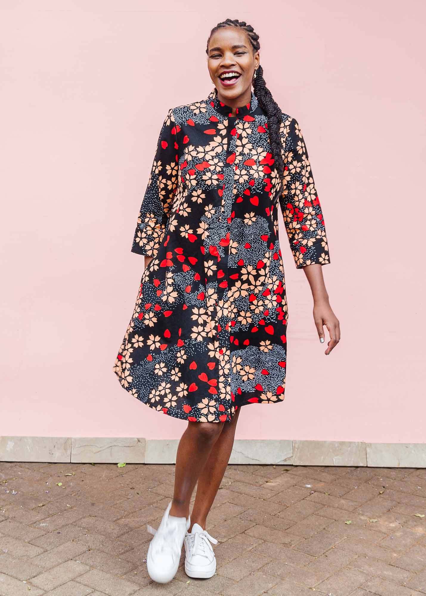 The model is wearing black dress with beige flowers and red hearts 