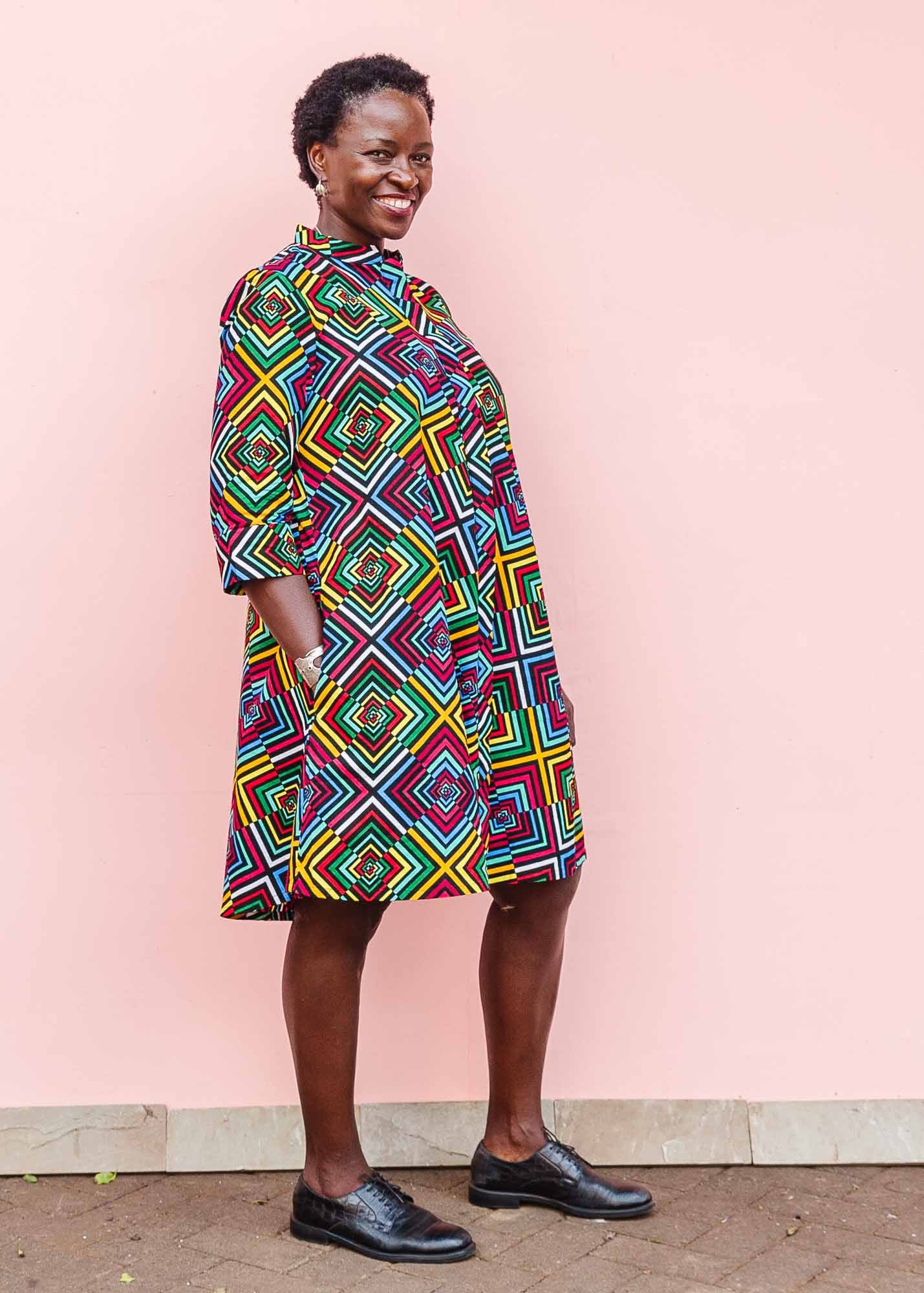 The model is wearing geometric print with rainbow colored dress 