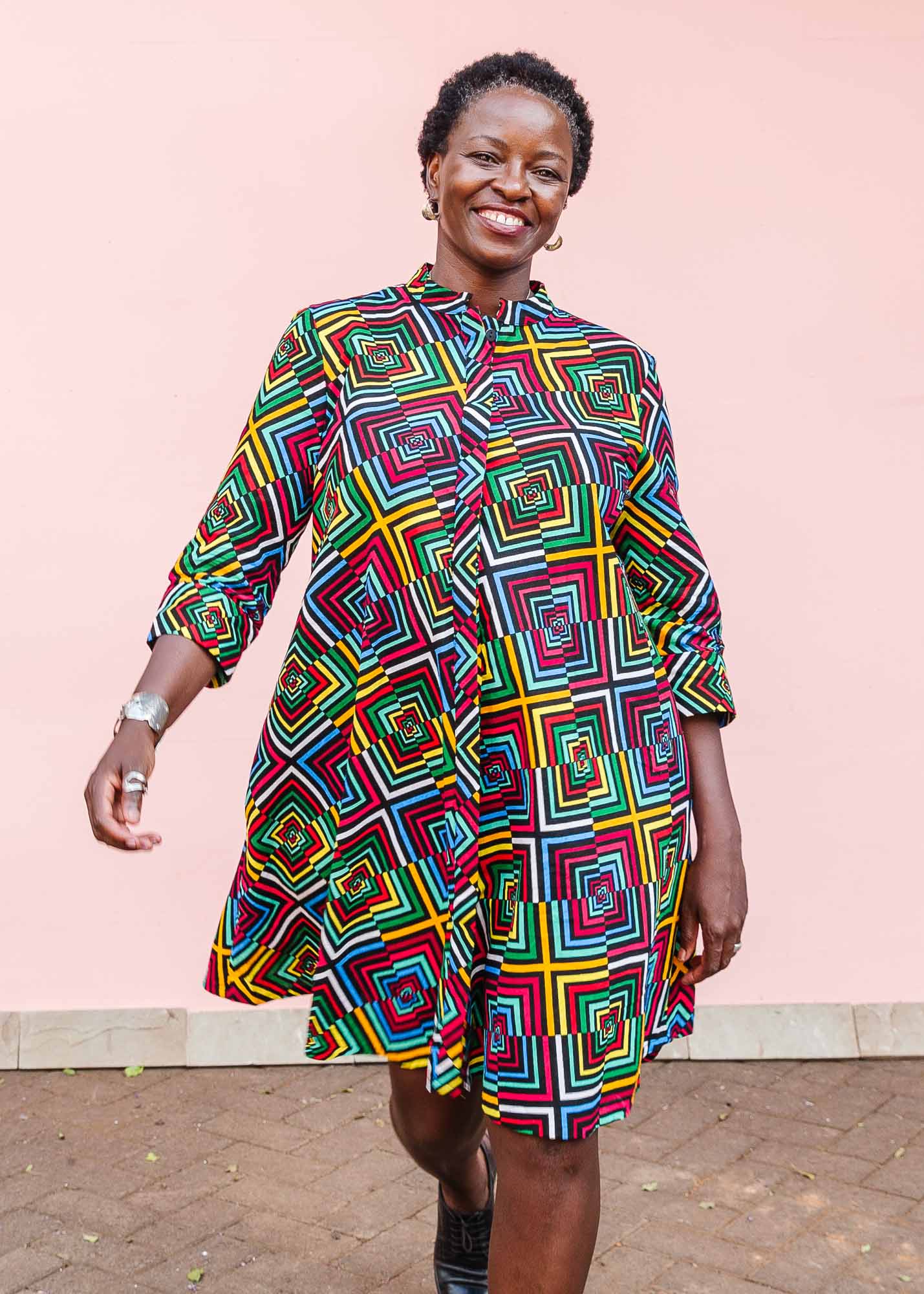 The model is wearing geometric print with rainbow colored dress 