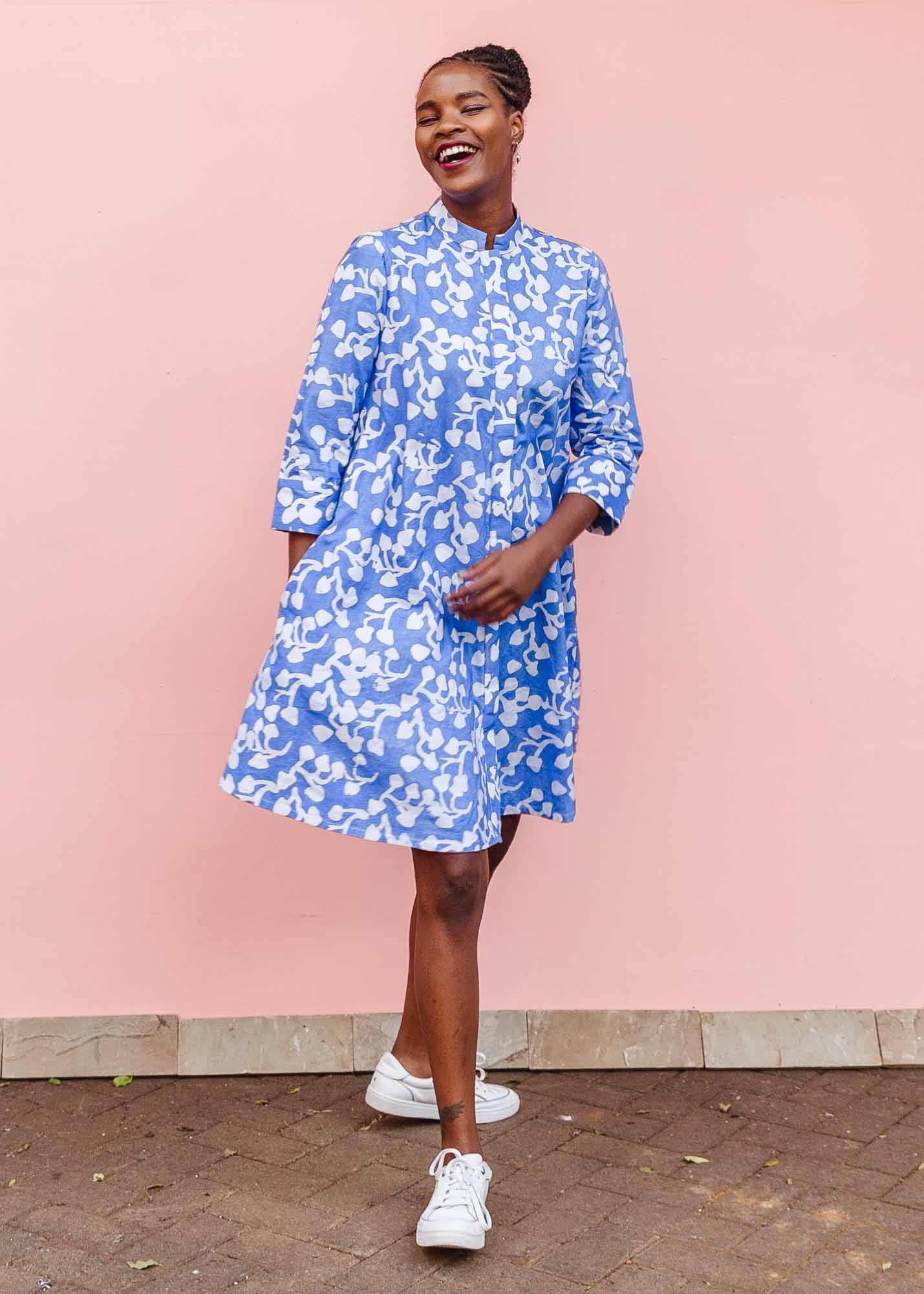 The model is wearing blue and white leaf print dress