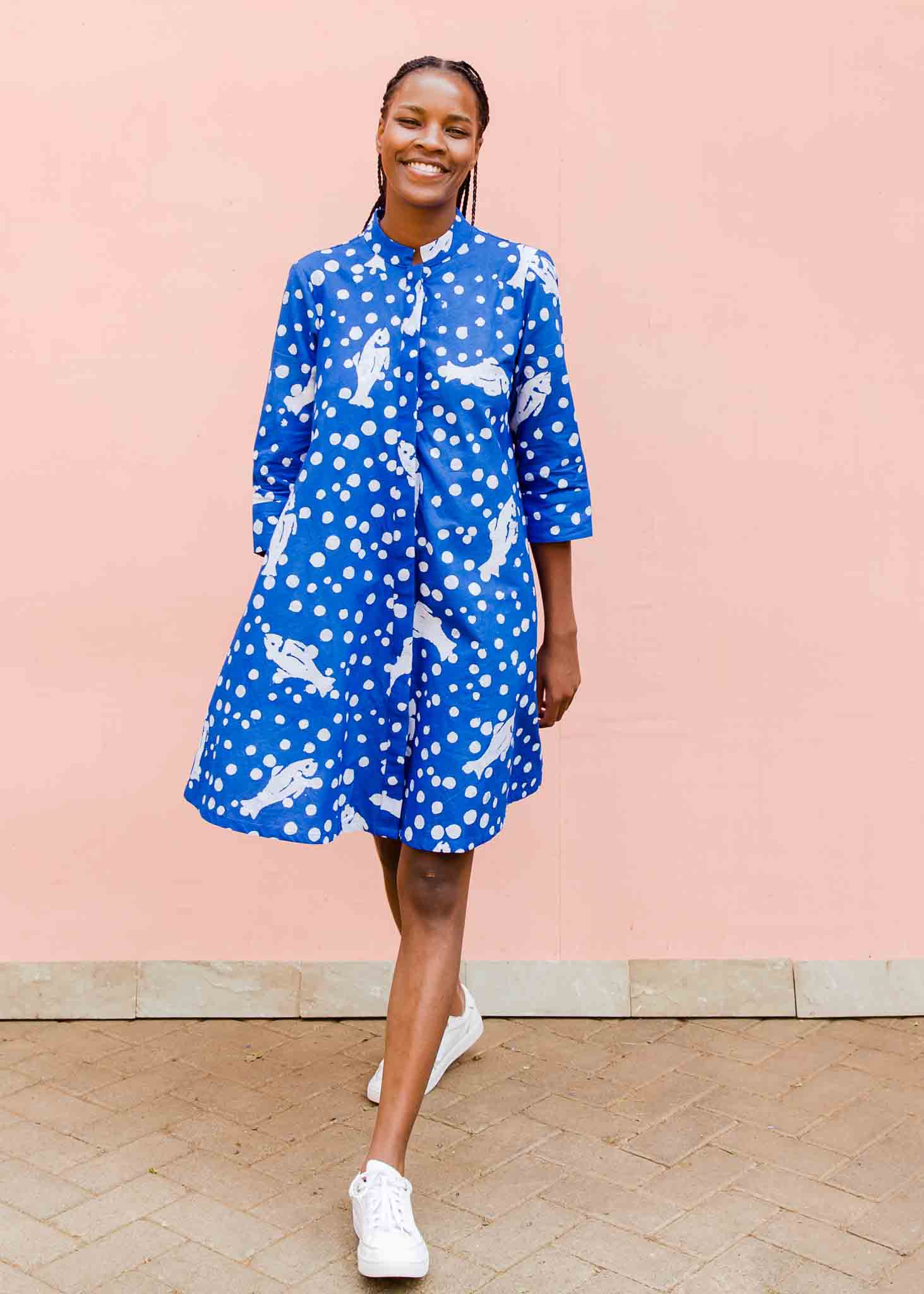 Model wearing blue dress with white fishes and polka dots.