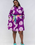 Woman wearing a purple floral dress with a colorful belt that is sold separately on a white background