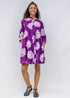 Woman wearing a purple floral dress against a white background