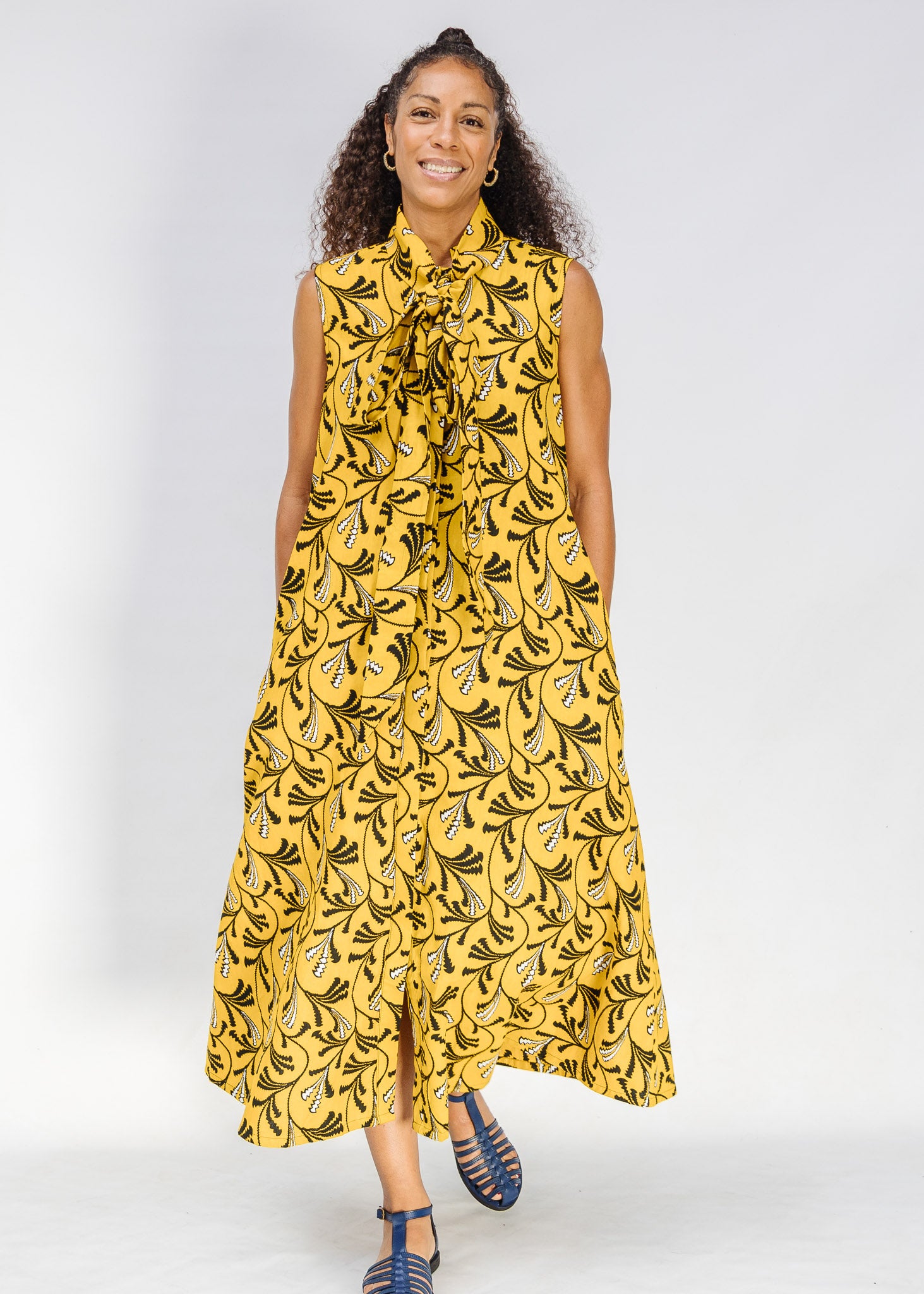 Model wearing yellow dress with black and white paisley print.