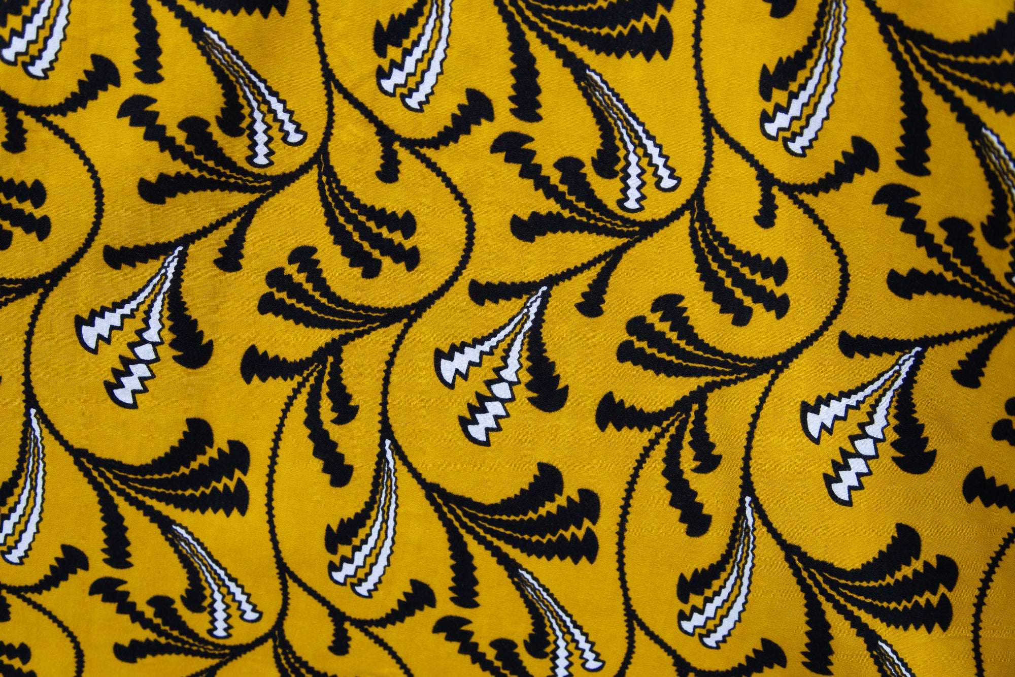 Close up display of yellow dress with black and white paisley print, fabric.