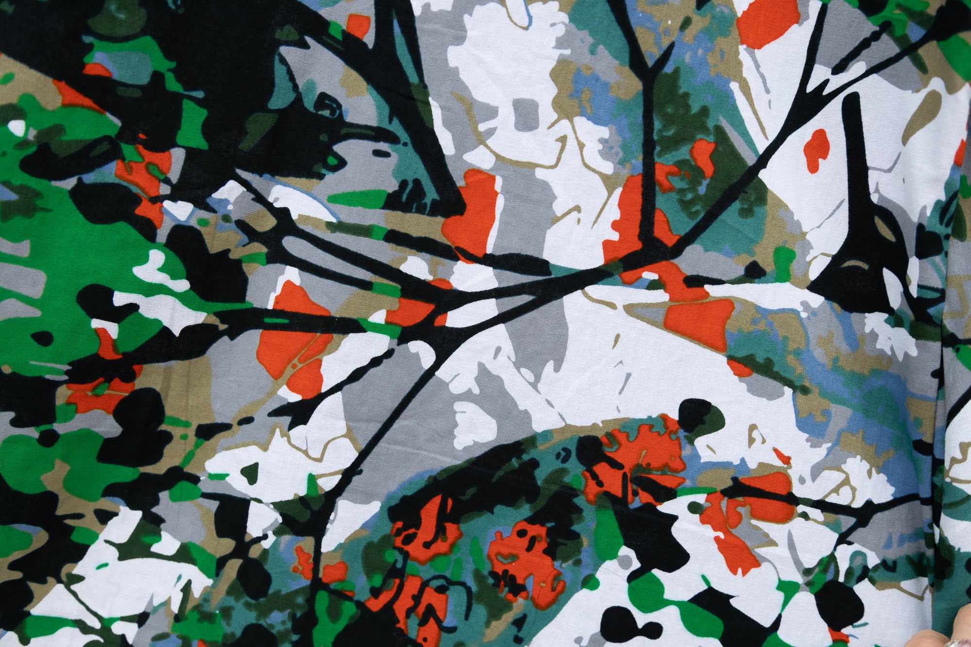 Close up display of green, grey, white, orange and black abstract print, fabric.