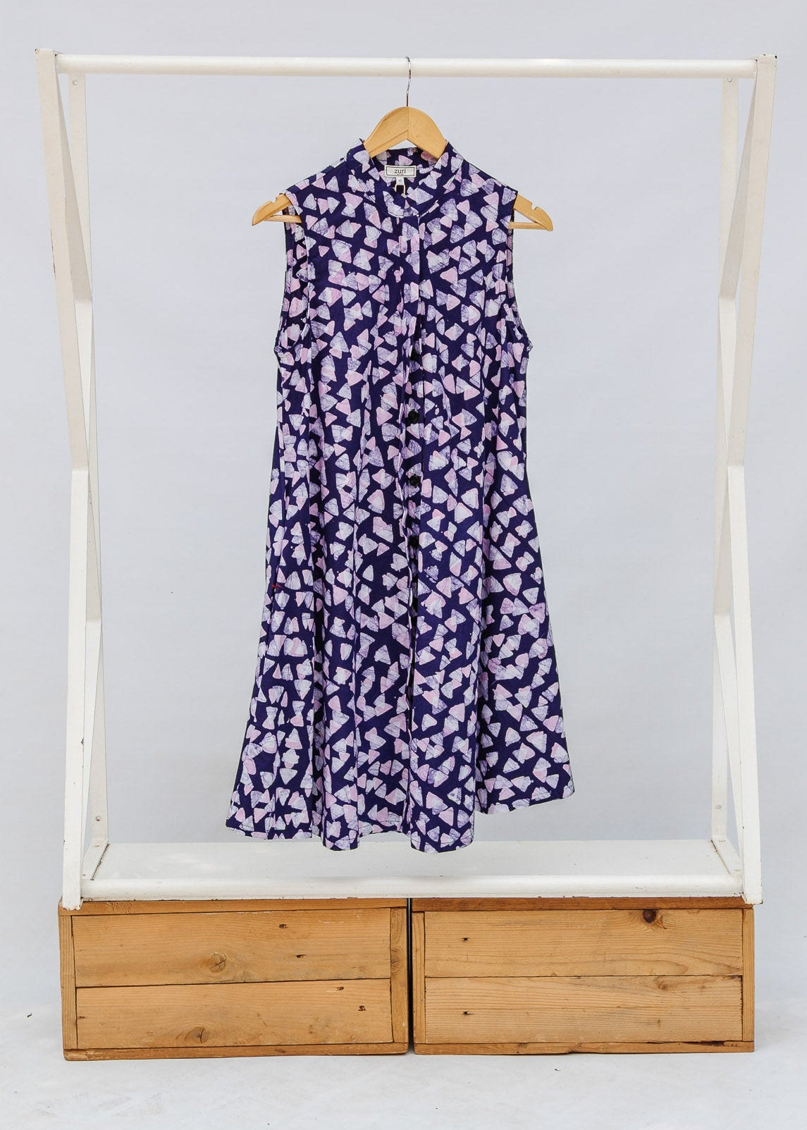 Purple dress on a hanger inside a wooden frame with white background
