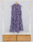 Purple dress on a hanger inside a wooden frame with white background