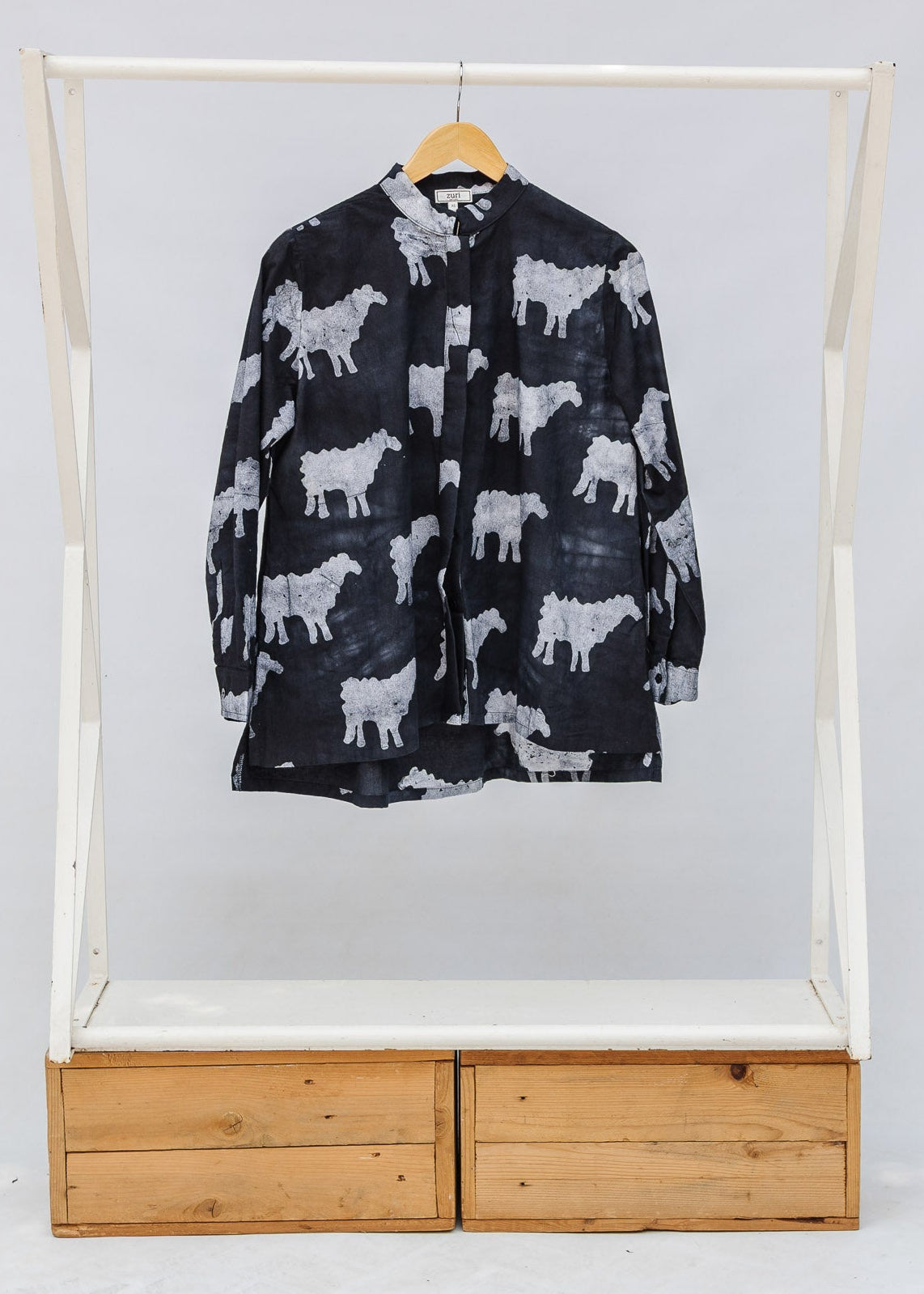 Black shirt with white animal pattern on a wooden rack against a white background