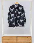 Black shirt with white animal pattern on a wooden rack against a white background