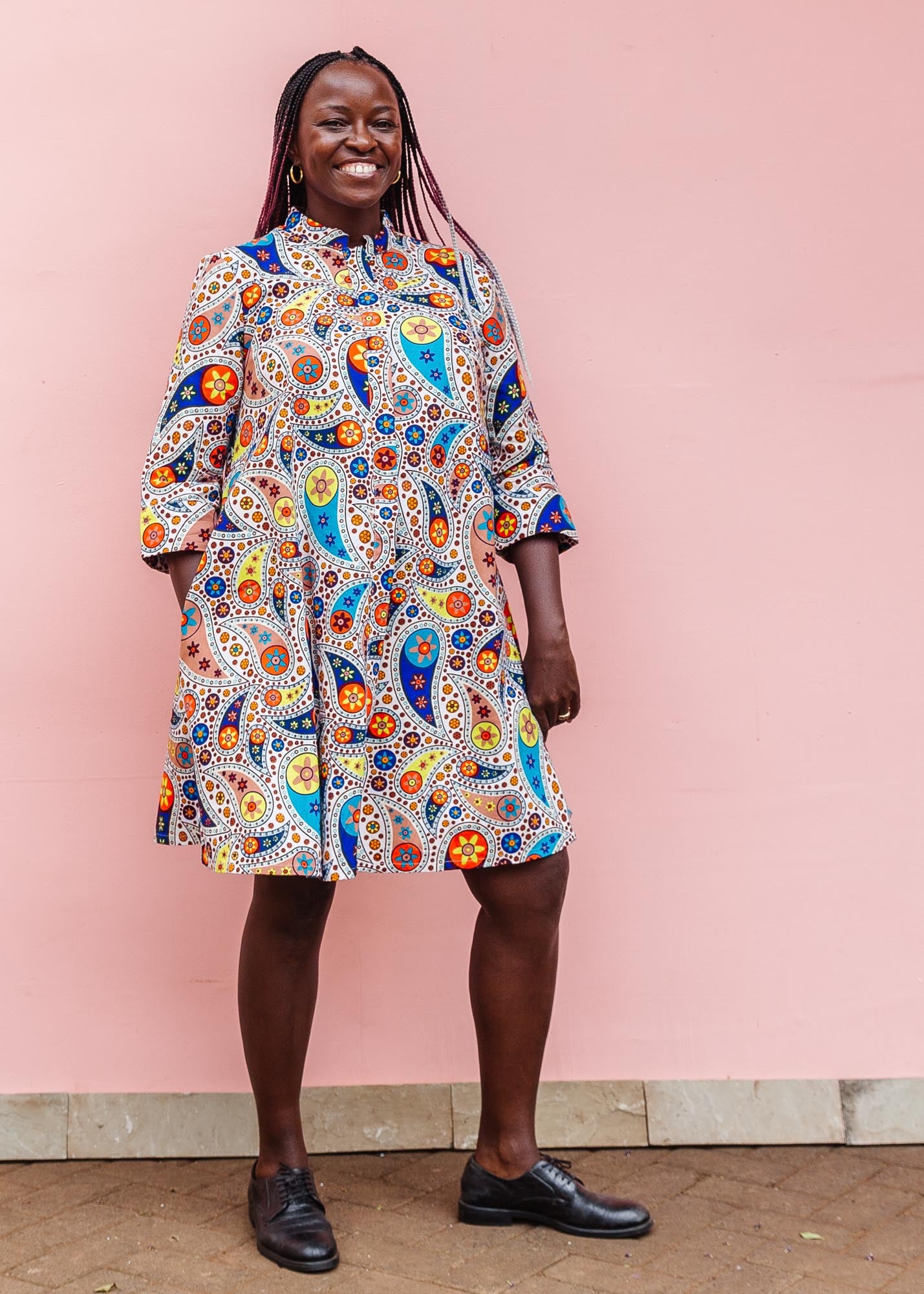 The model is wearing multi-colored paisley print dress