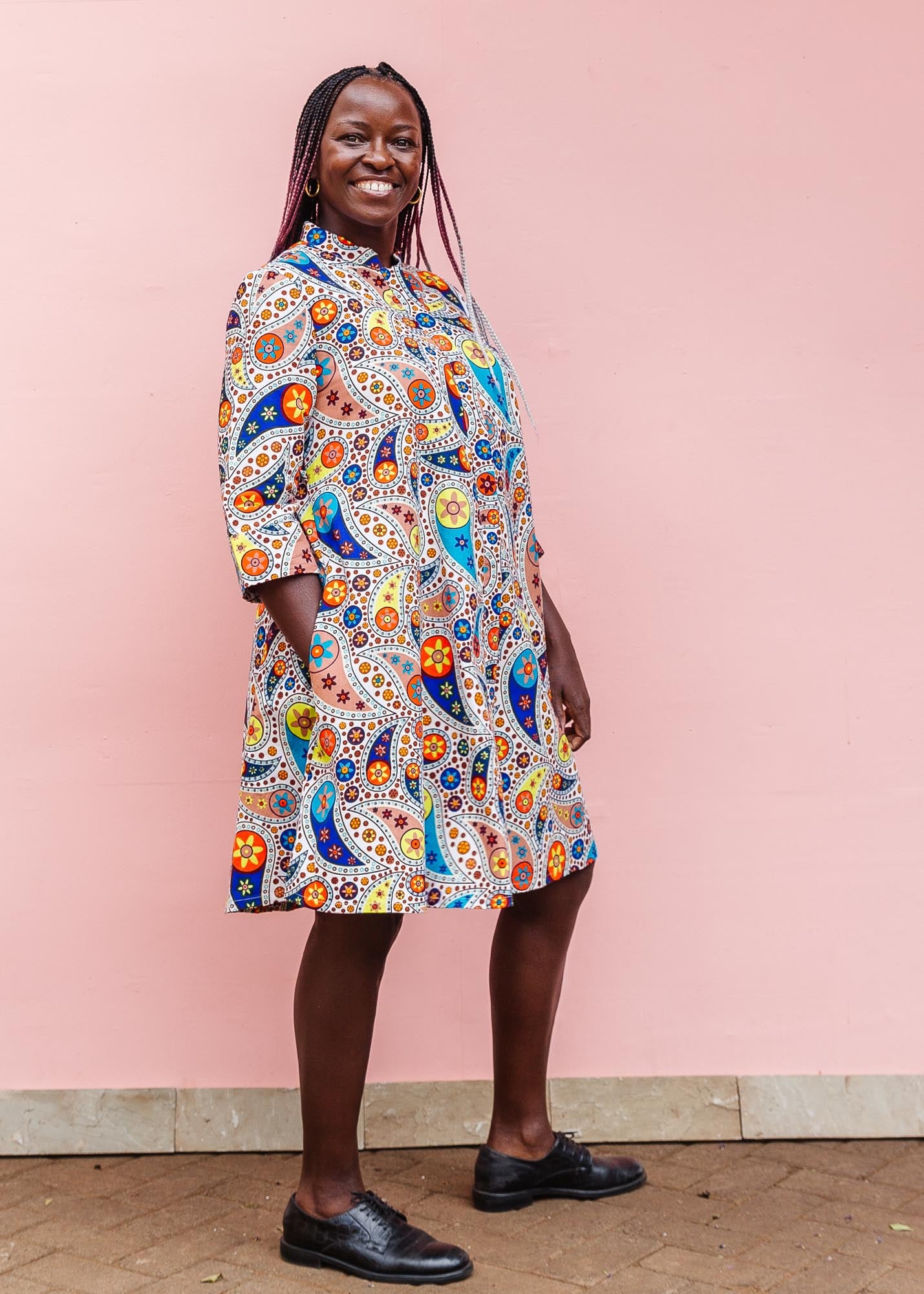 The model is wearing multi-colored paisley print dress