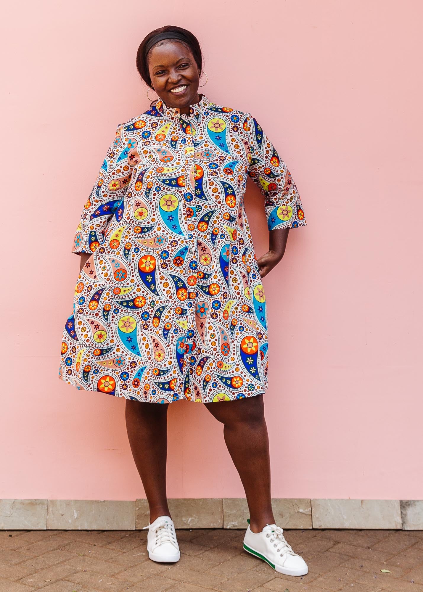 The model is wearing multi-colored paisley print dress