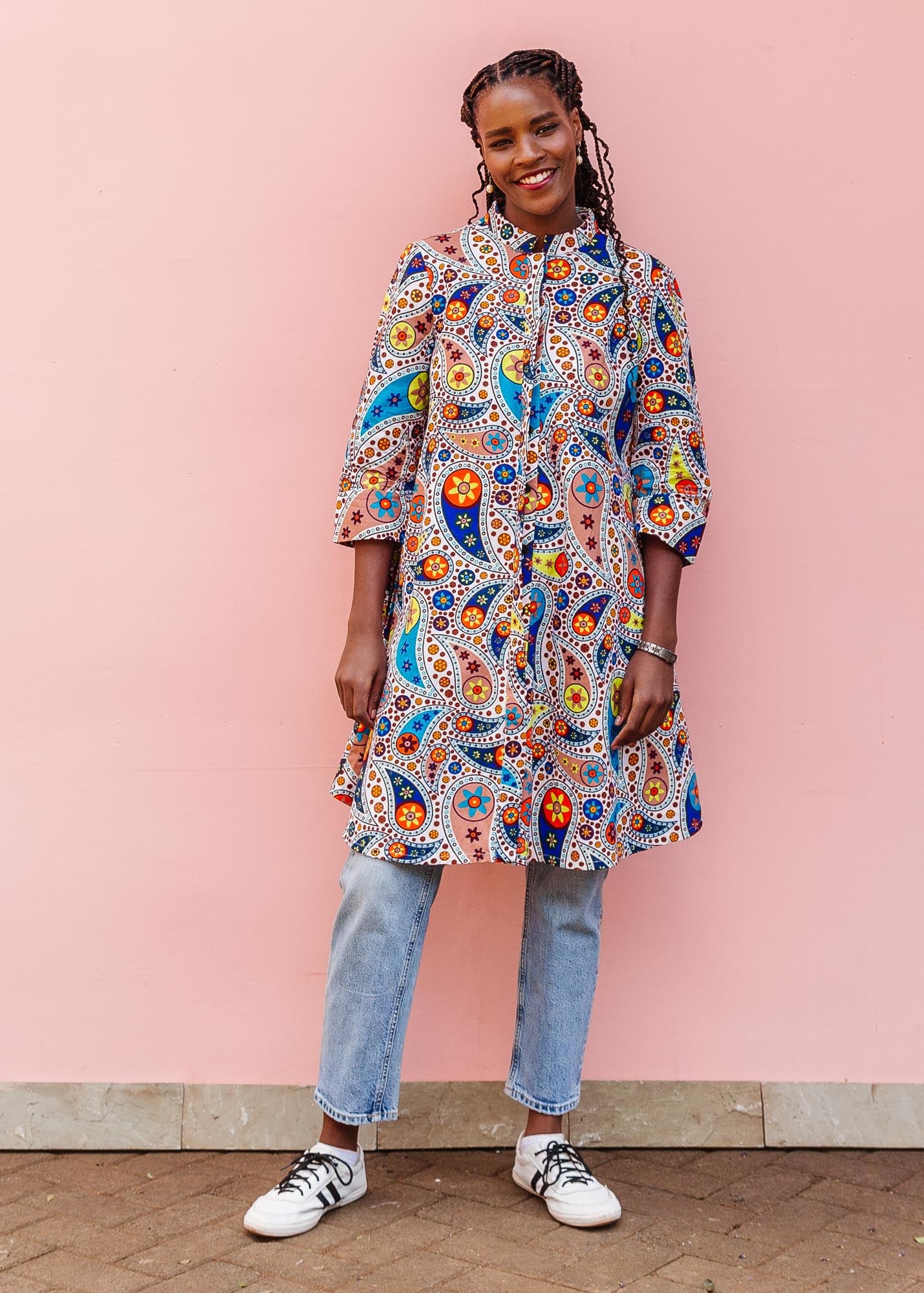 The model is wearing multi-colored paisley print dress