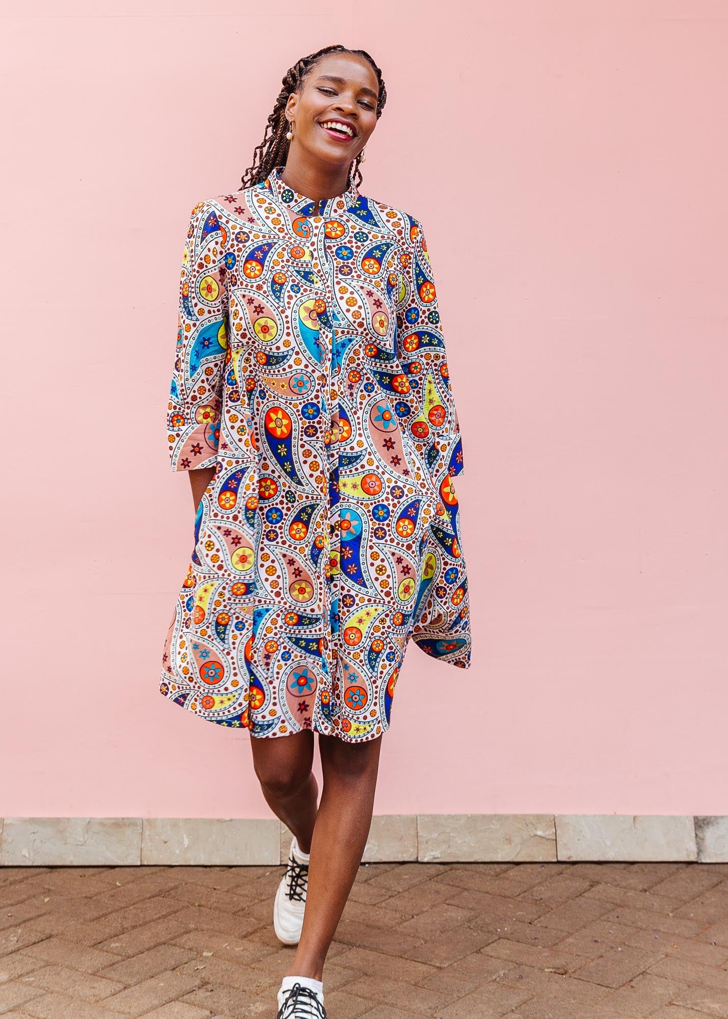 The model is wearing multi-colored paisley print dress