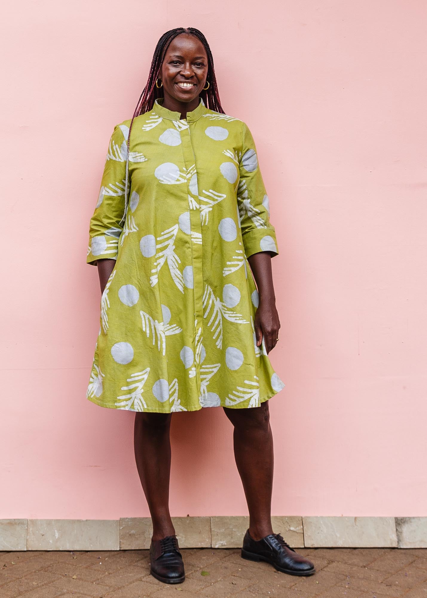 The model is wearing olive-green, white and green batik dress