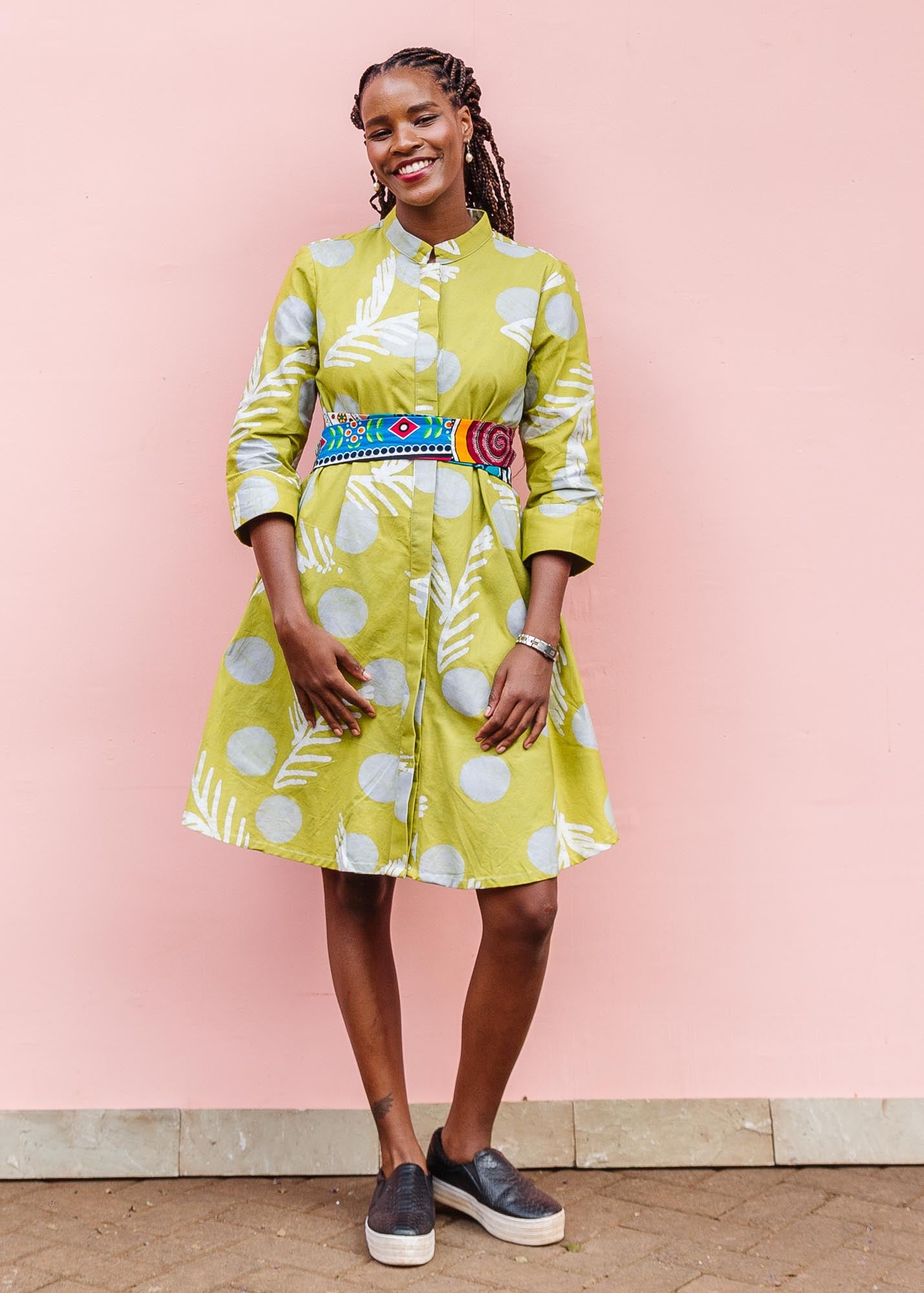 The model is wearing olive-green, white and green batik dress