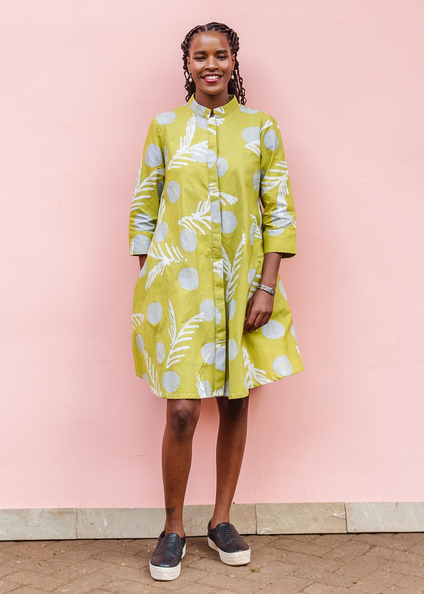 The model is wearing olive-green, white and green batik dress