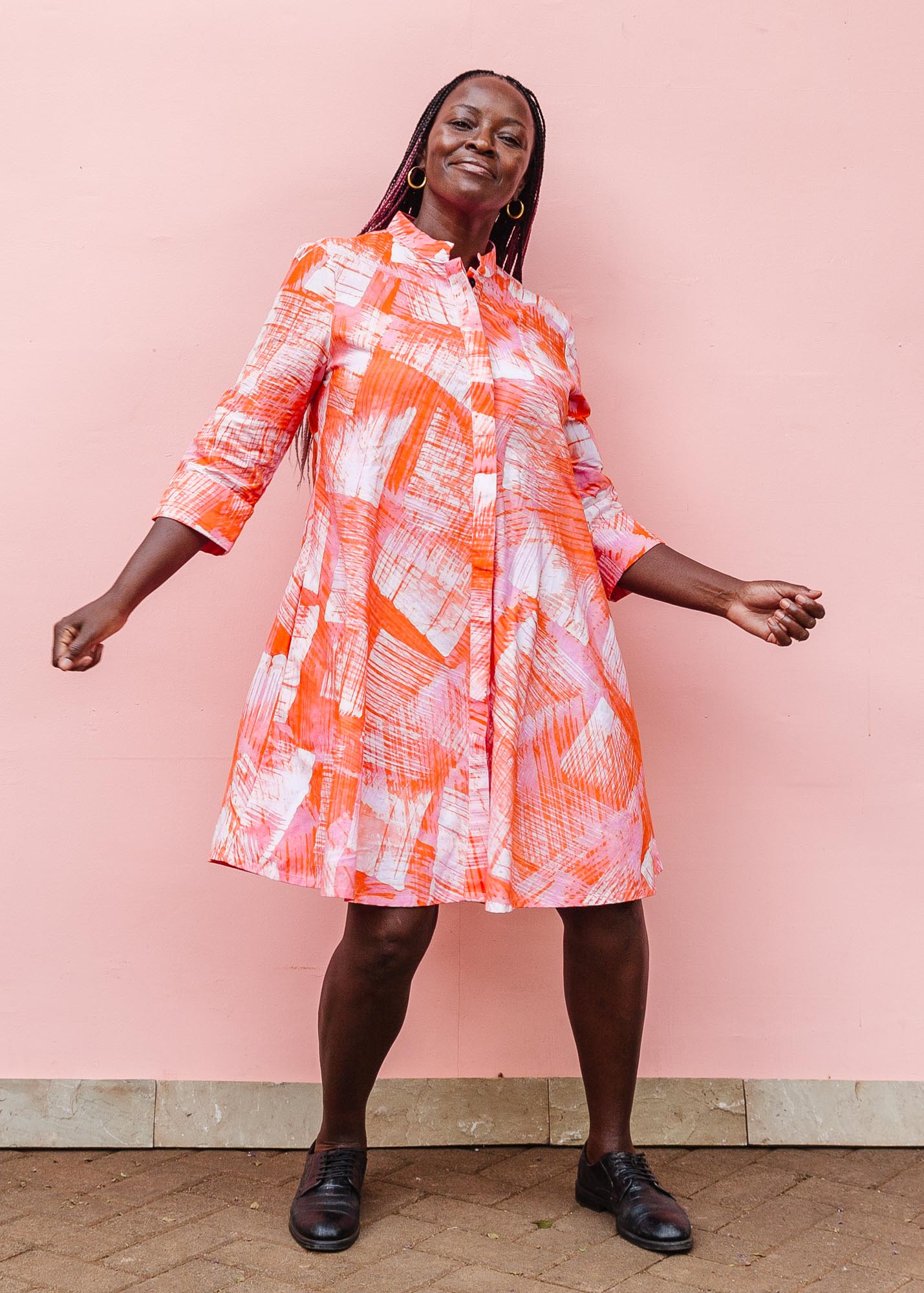 The model is wearing orange, pink and white brushstrokes batik dress 