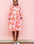 The model is wearing orange, pink and white brushstrokes batik dress 