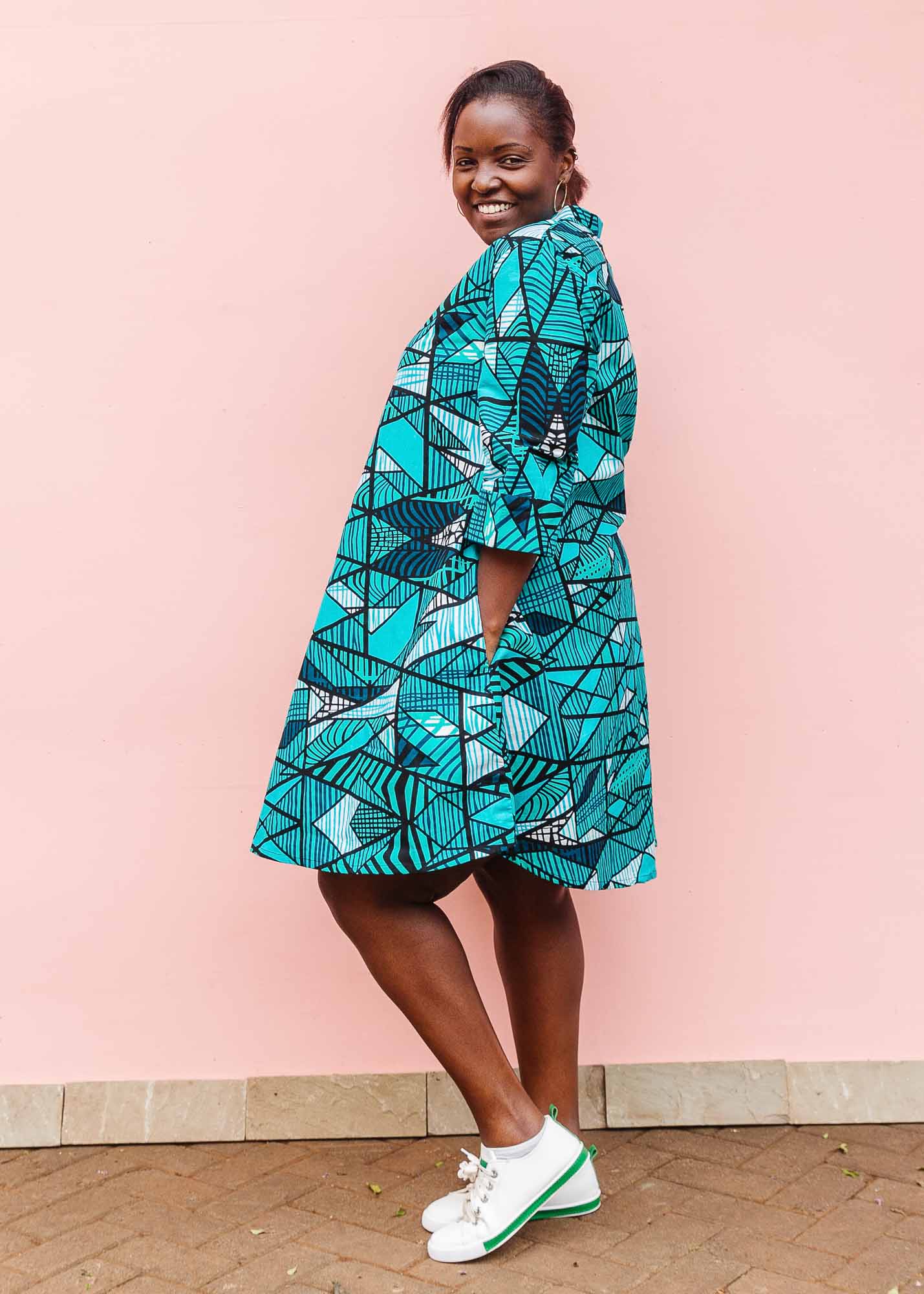 The model is wearing turquoise geometric print dress