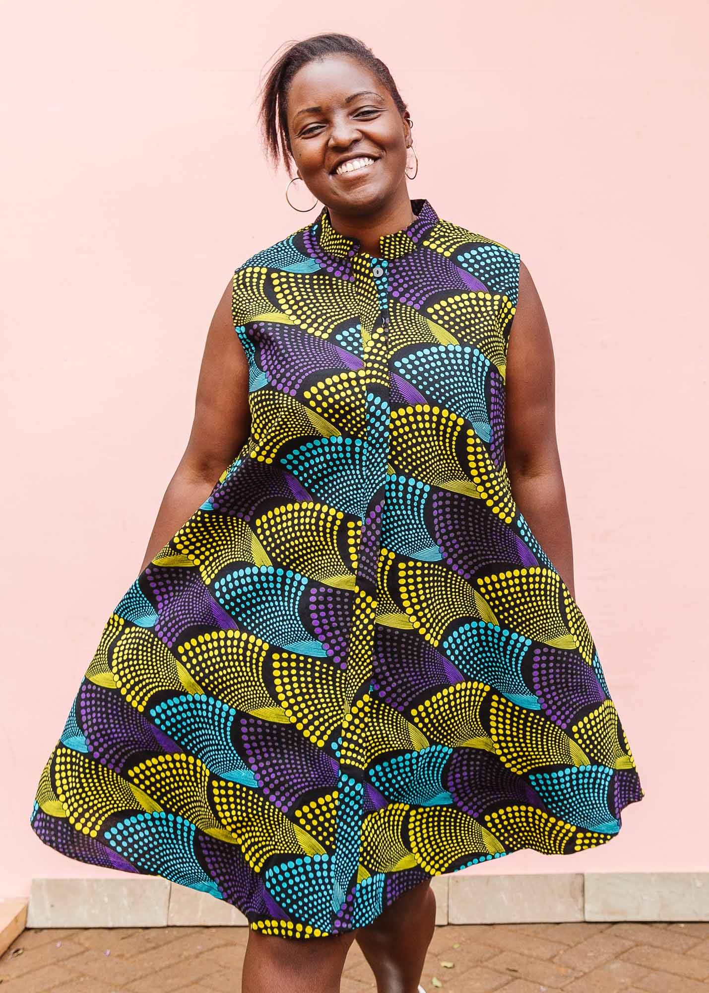 The model is wearing black dress with purple , yellow and turquoise dotted fans 