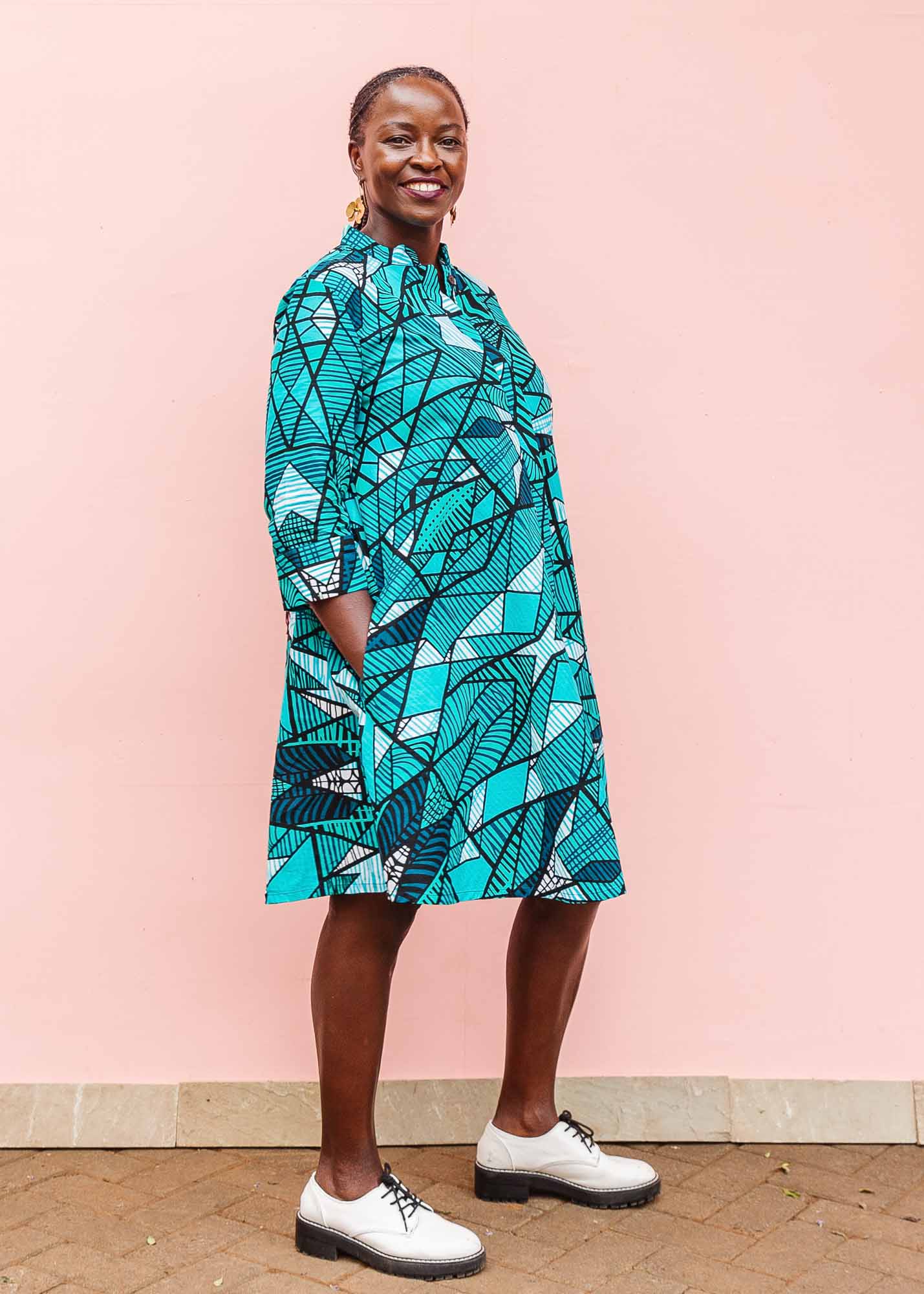 The model is wearing turquoise geometric print dress