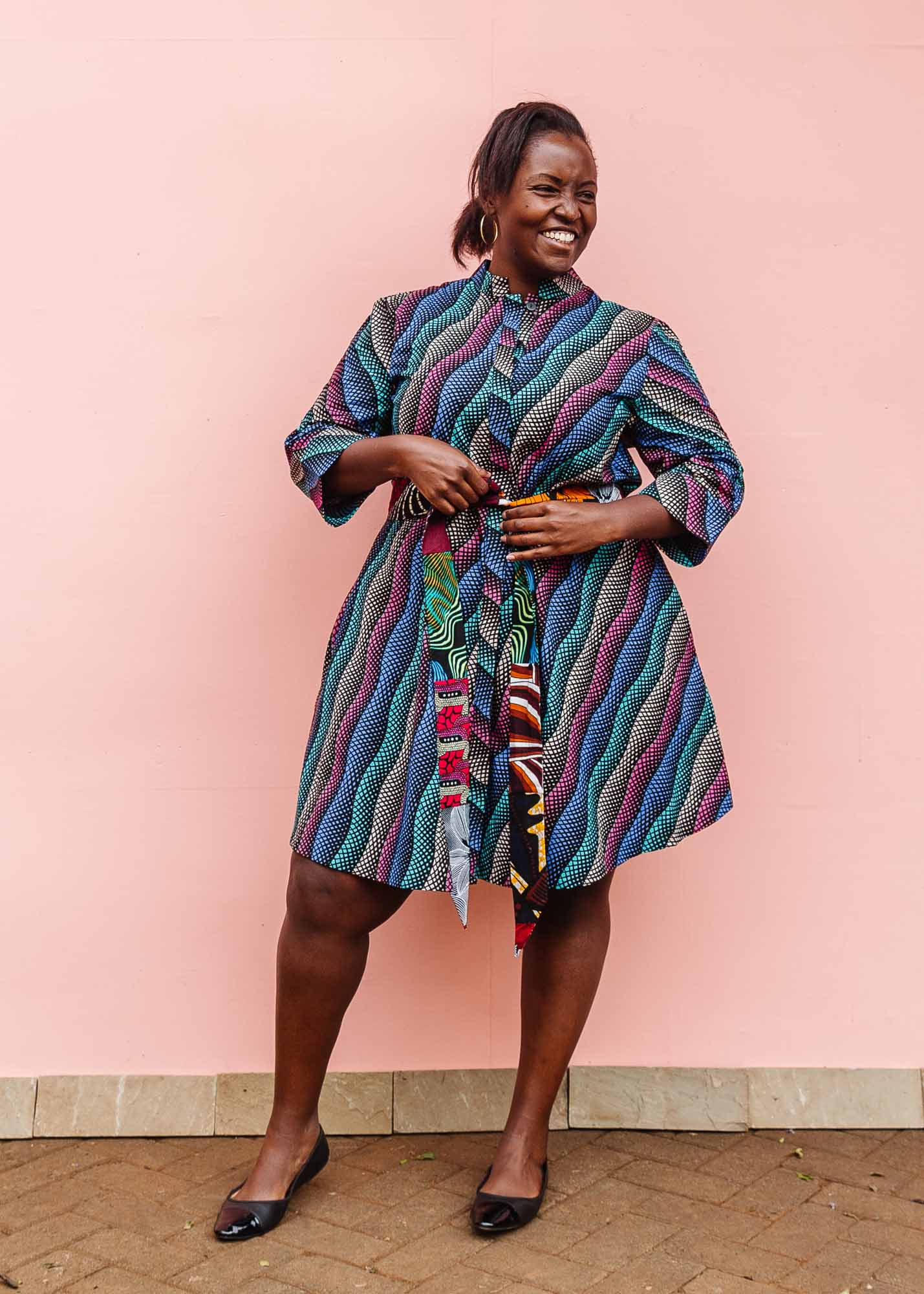 The model is wearing pink, blue, turquoise and beige abstract line dress.