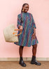 The model is wearing pink, blue, turquoise and beige abstract line dress.