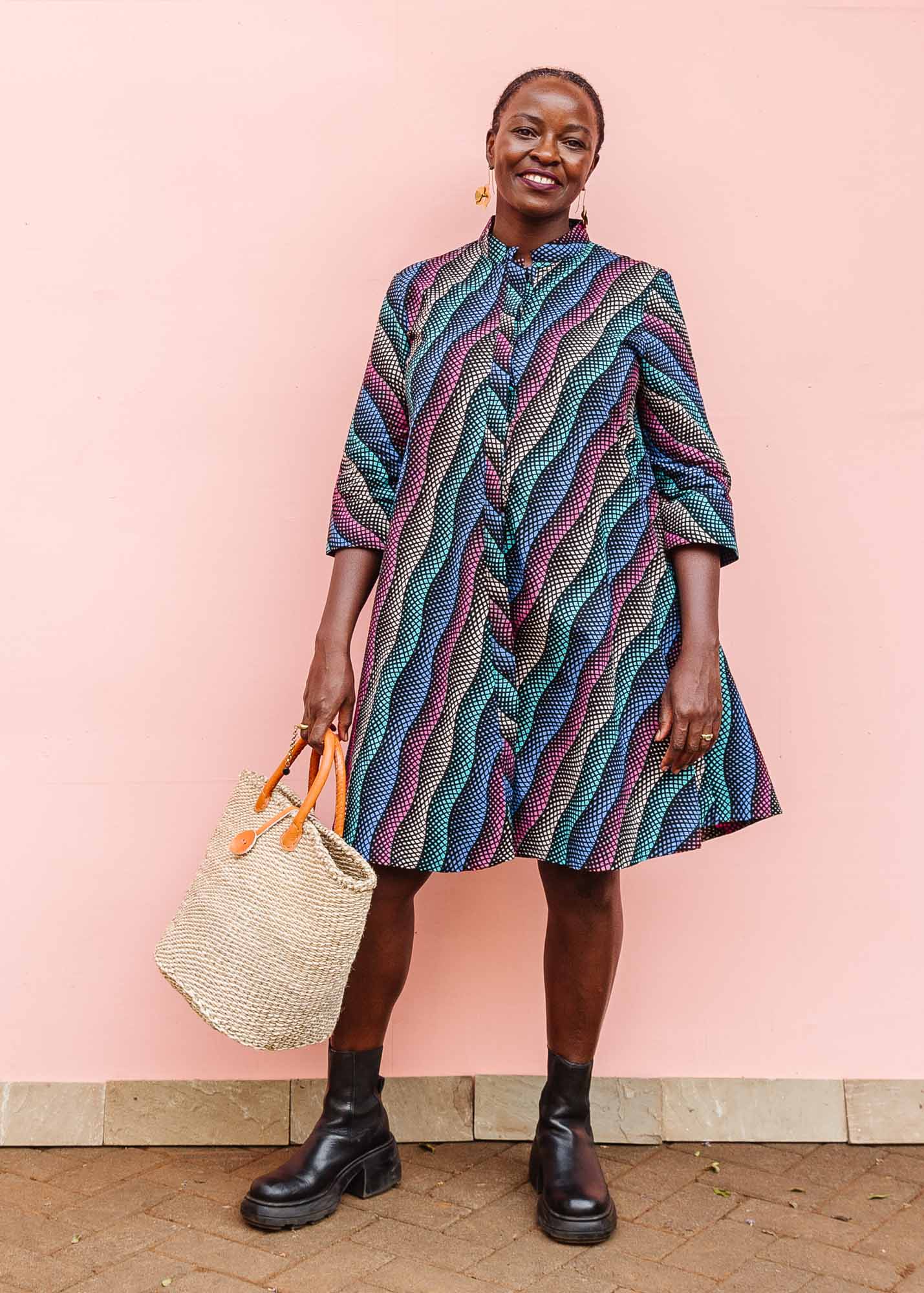 The model is wearing pink, blue, turquoise and beige abstract line dress.