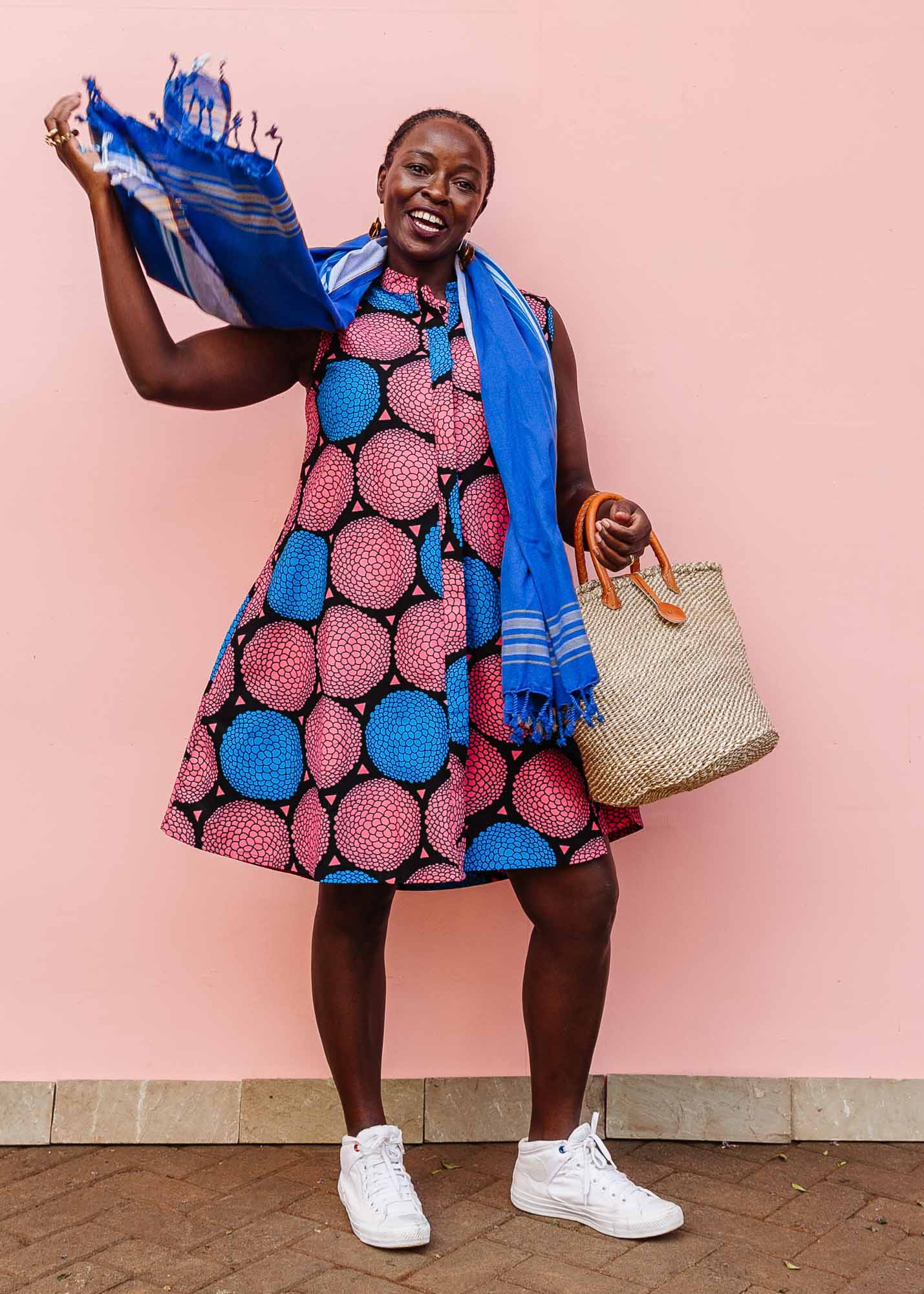 The model is wearing coral, blue and black circular print dress