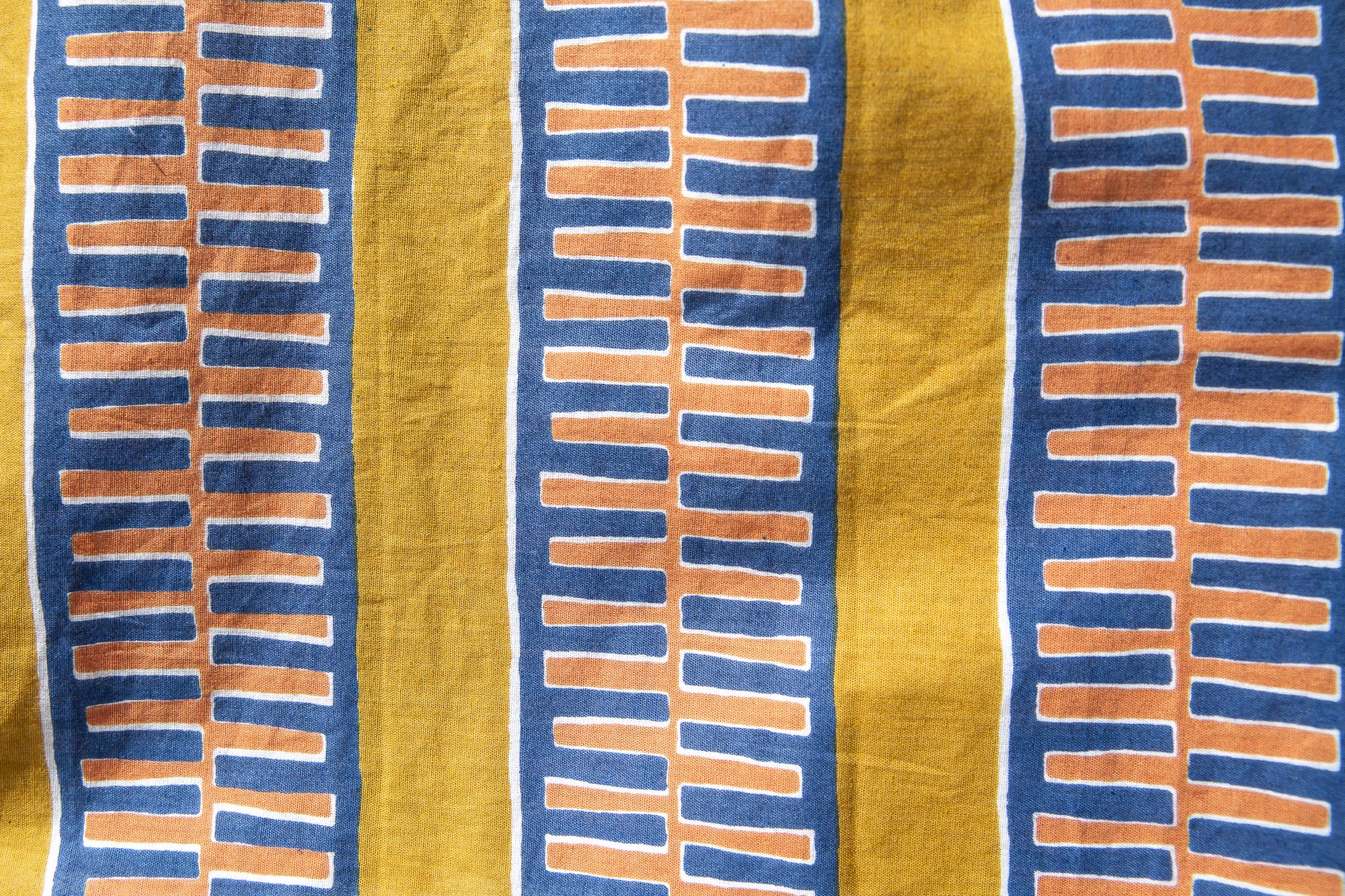 Close up display of yellow pants with blue stripe, fabric.