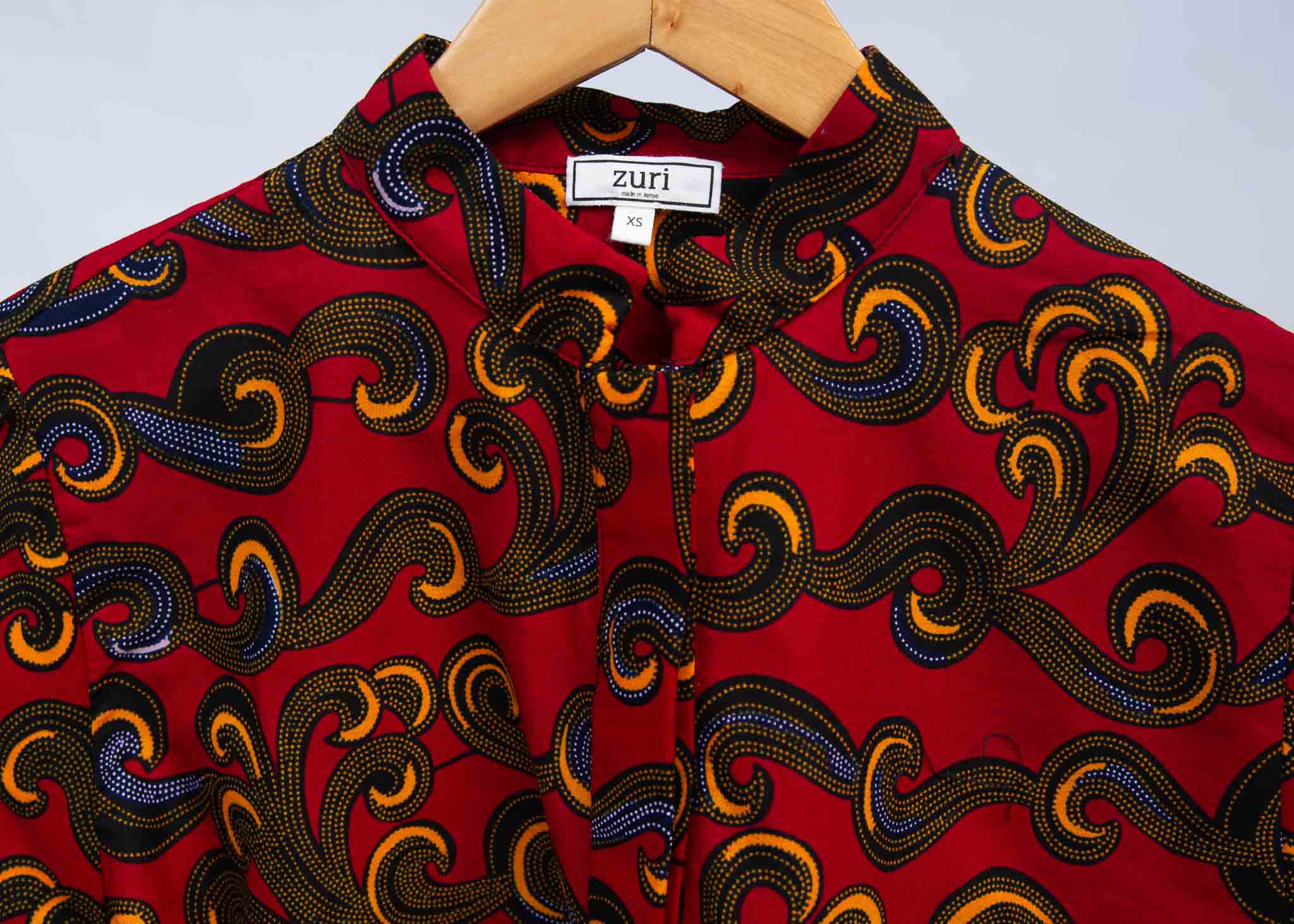 Display of red long sleeved blouse with yellow swirls.