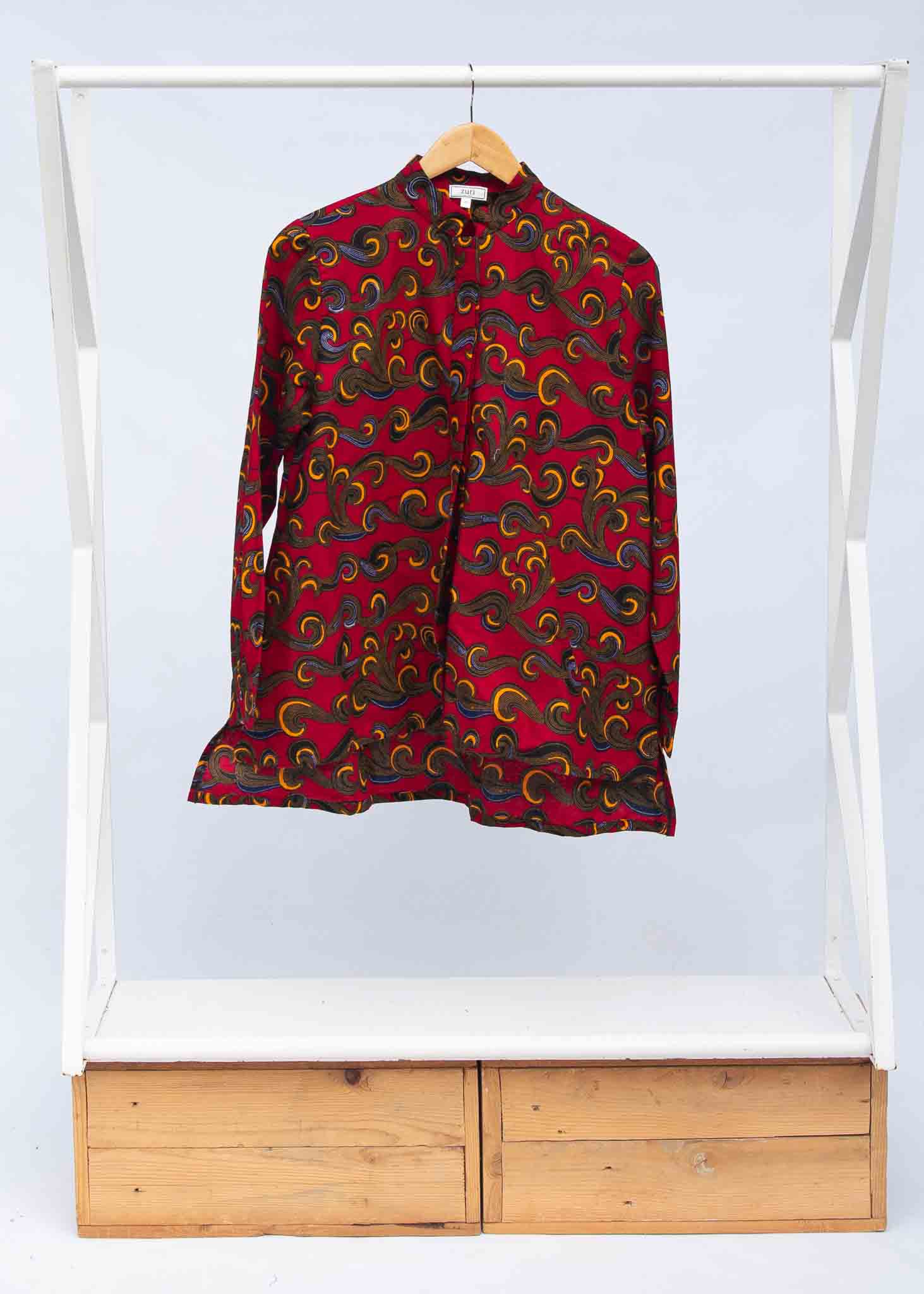 Display of red long sleeved blouse with yellow swirls.
