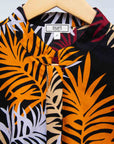Display of black dress with orange, red and white leaf print.