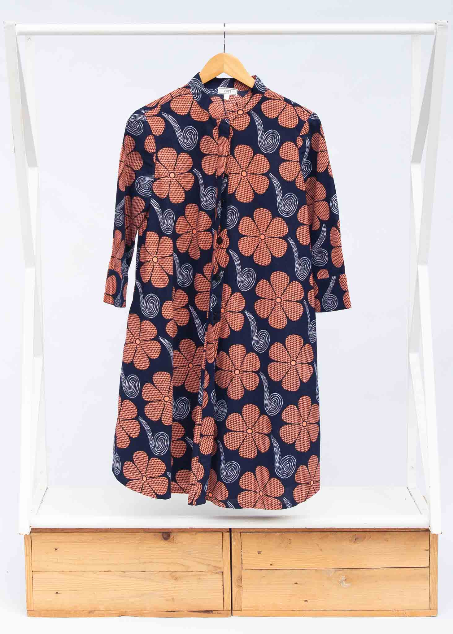 Display of navy dress with brown flowers and white swirls.