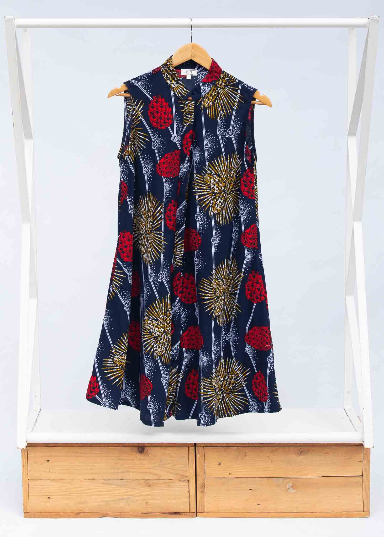 Display of navy sleeveless dress with red, yellow and white splatter print.