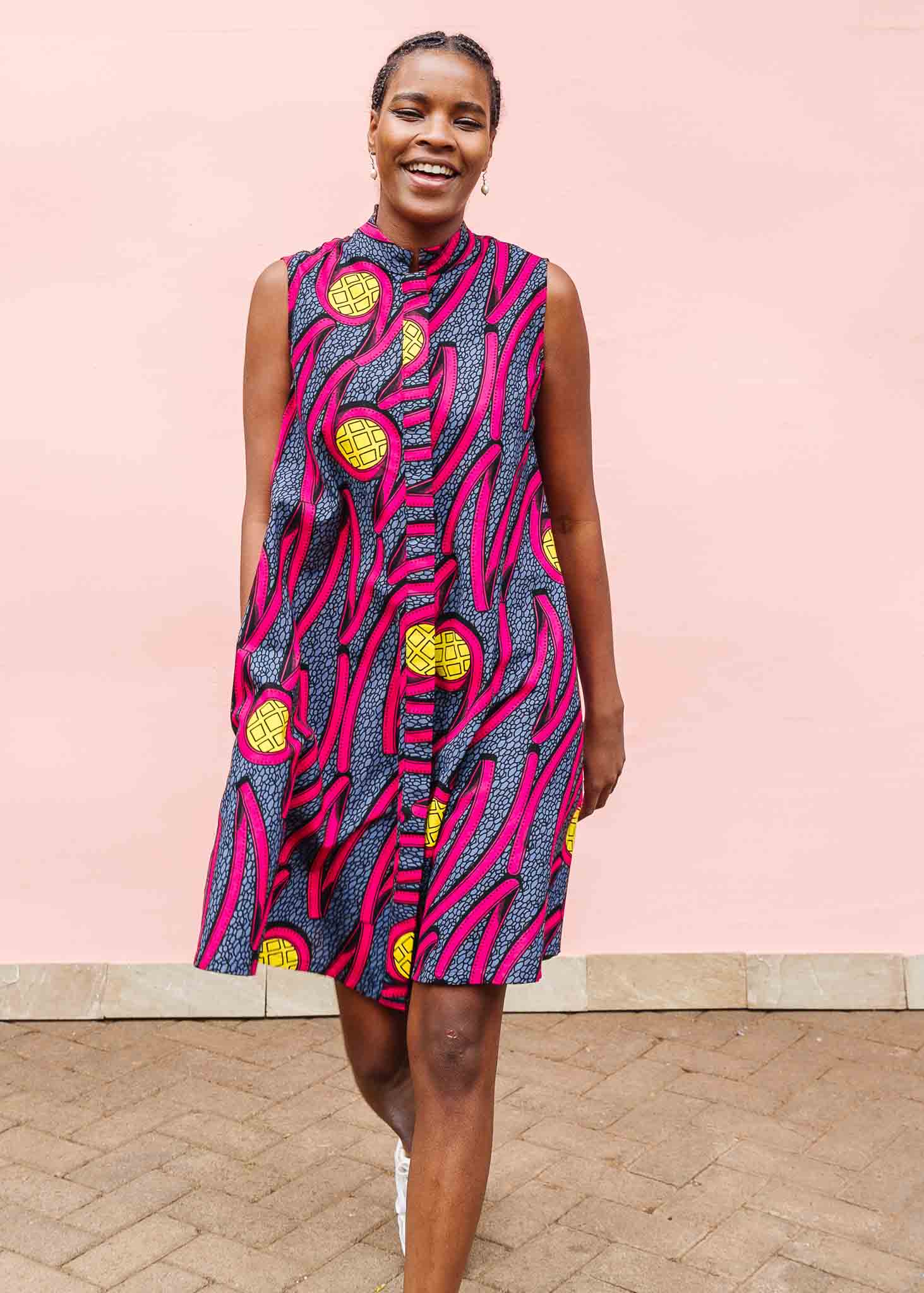 Model wearing sleeveless gray dress with bold pink lines and yellow circles.
