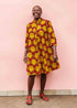 Model wearing red dress with yellow and brown flowers.