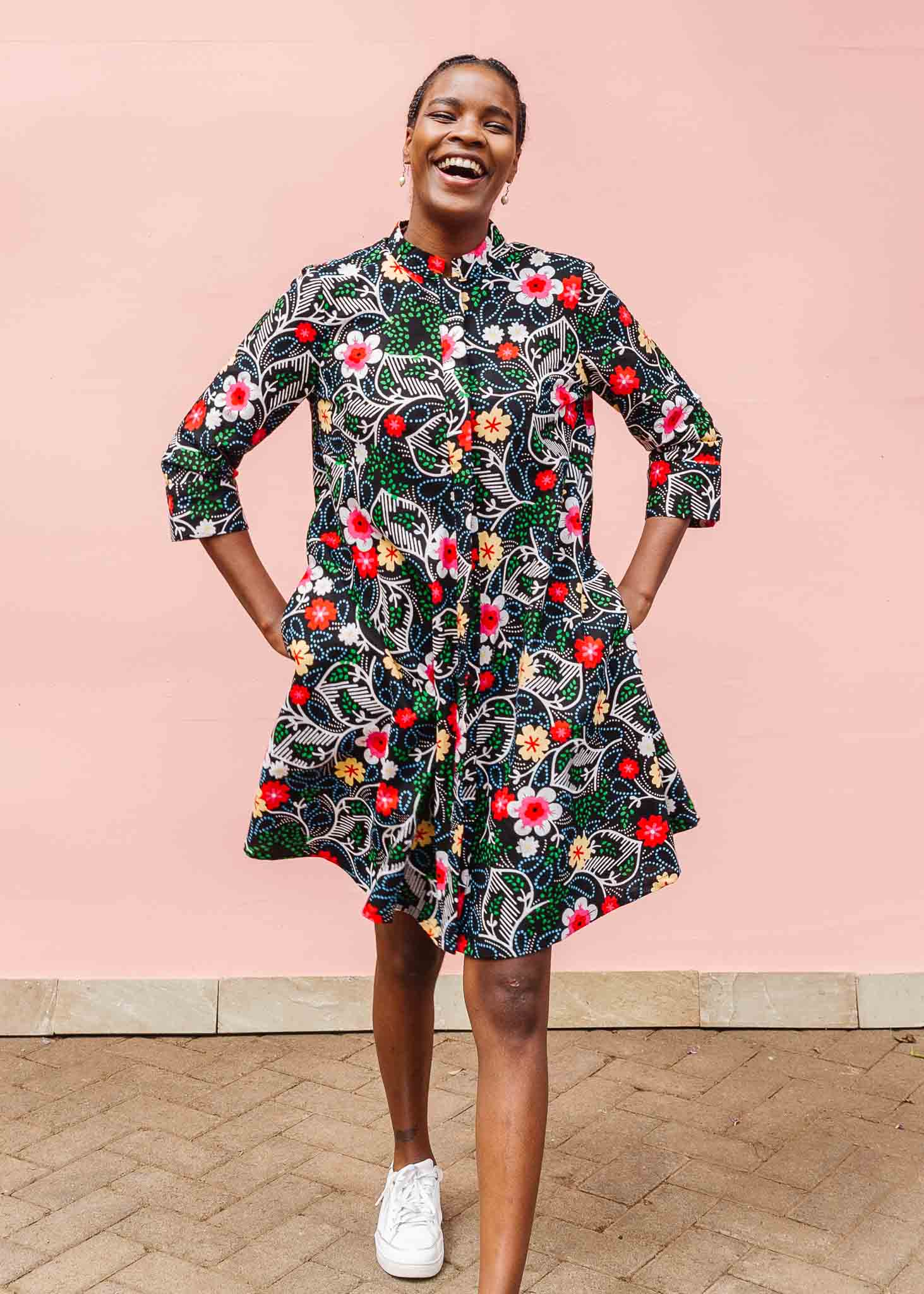 Model wearing black dress with white, green, red and yellow floral print.