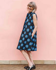 Model wearing black sleeveless dress with blue and white circle print.