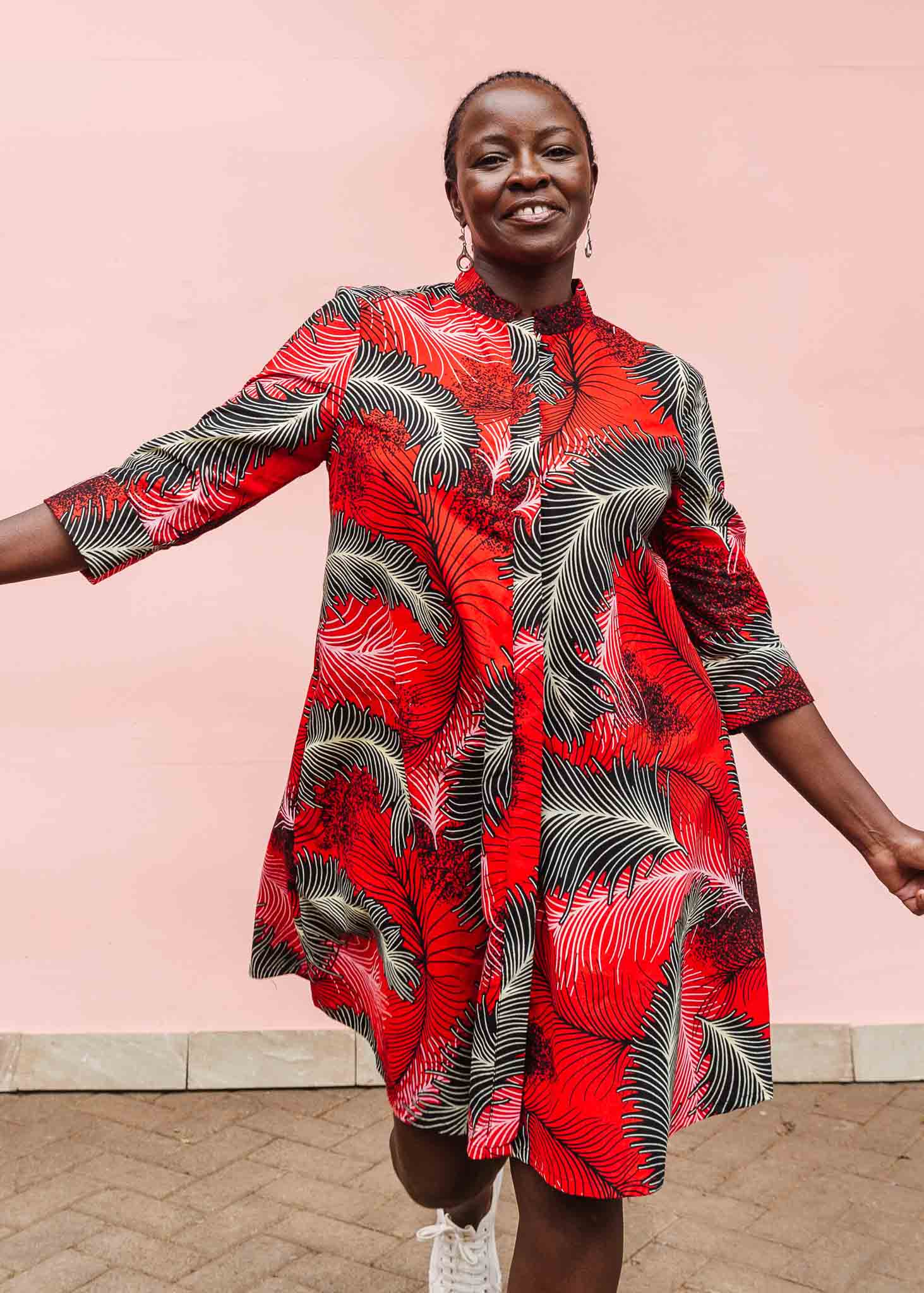 Model wearing red dress with black and white feather print.