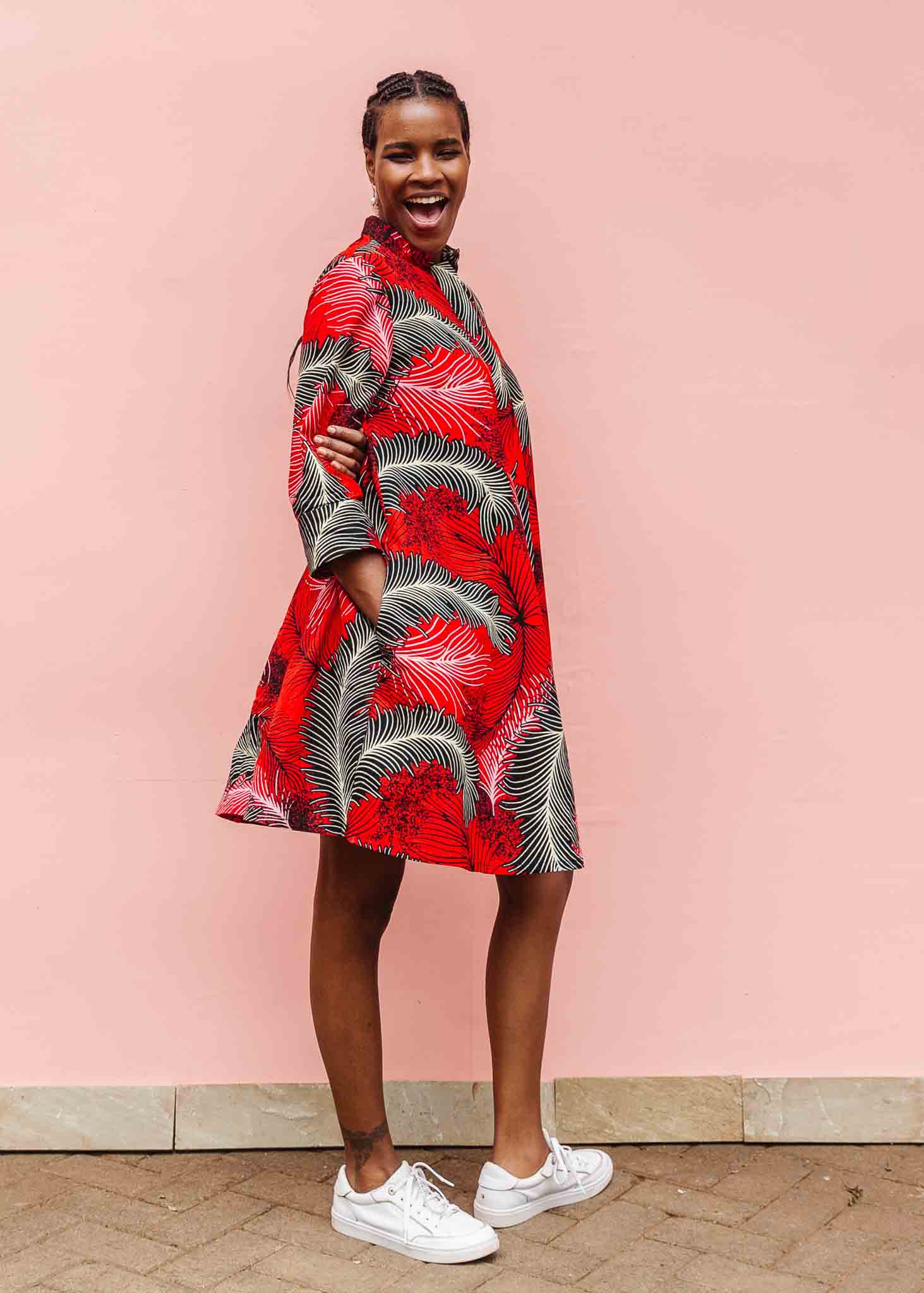 Model wearing red dress with black and white feather print.