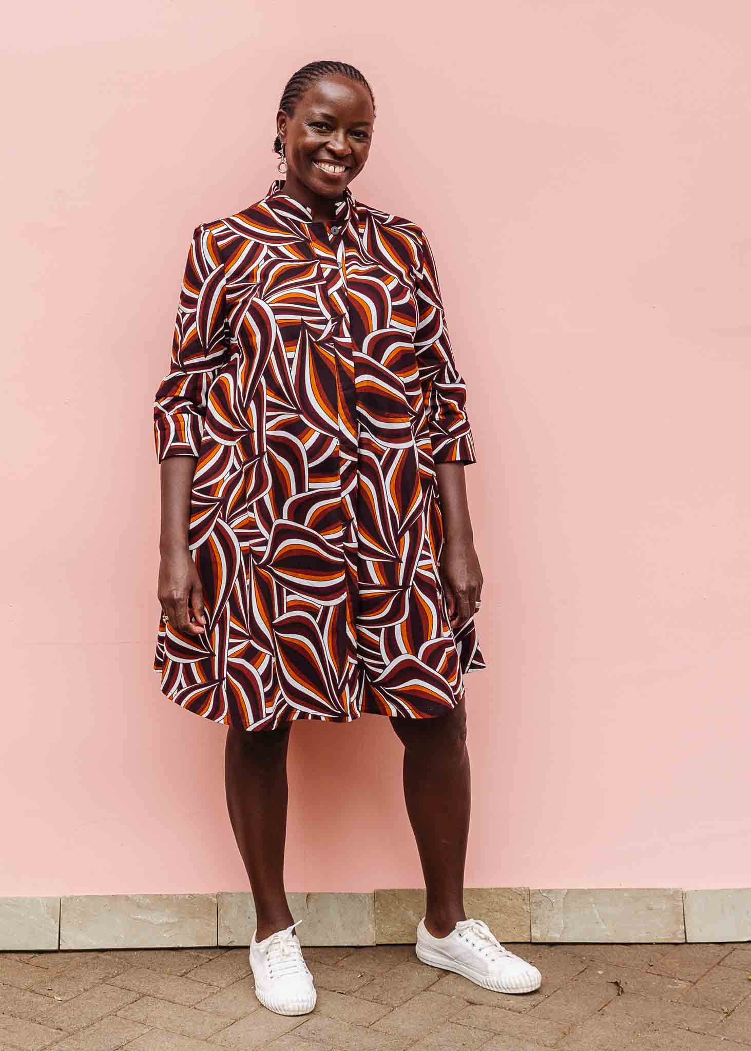 Model wearing brown, orange, burgundy and white abstract print dress.