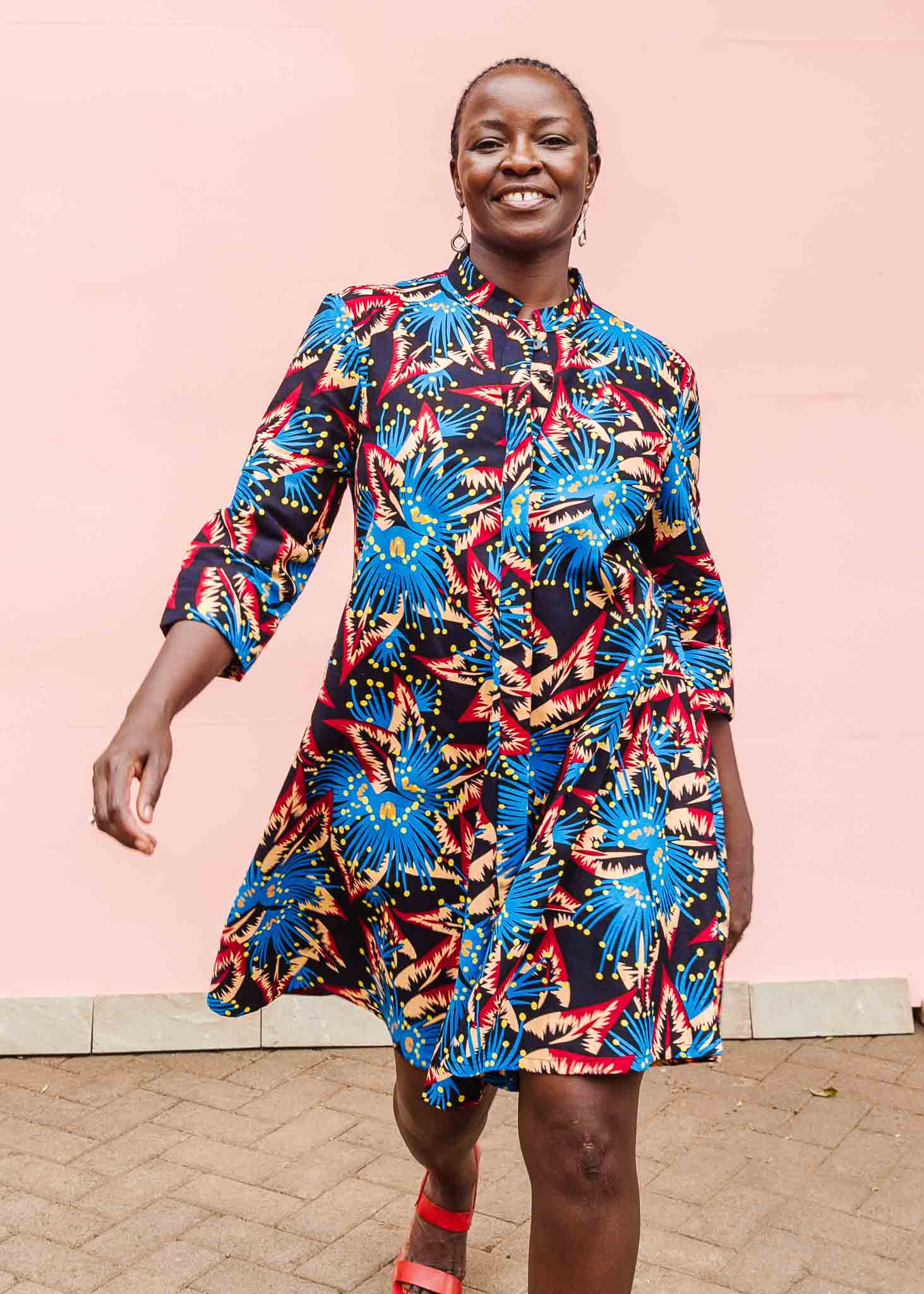 Model wearing black dress with blue, beige and red splatter print.