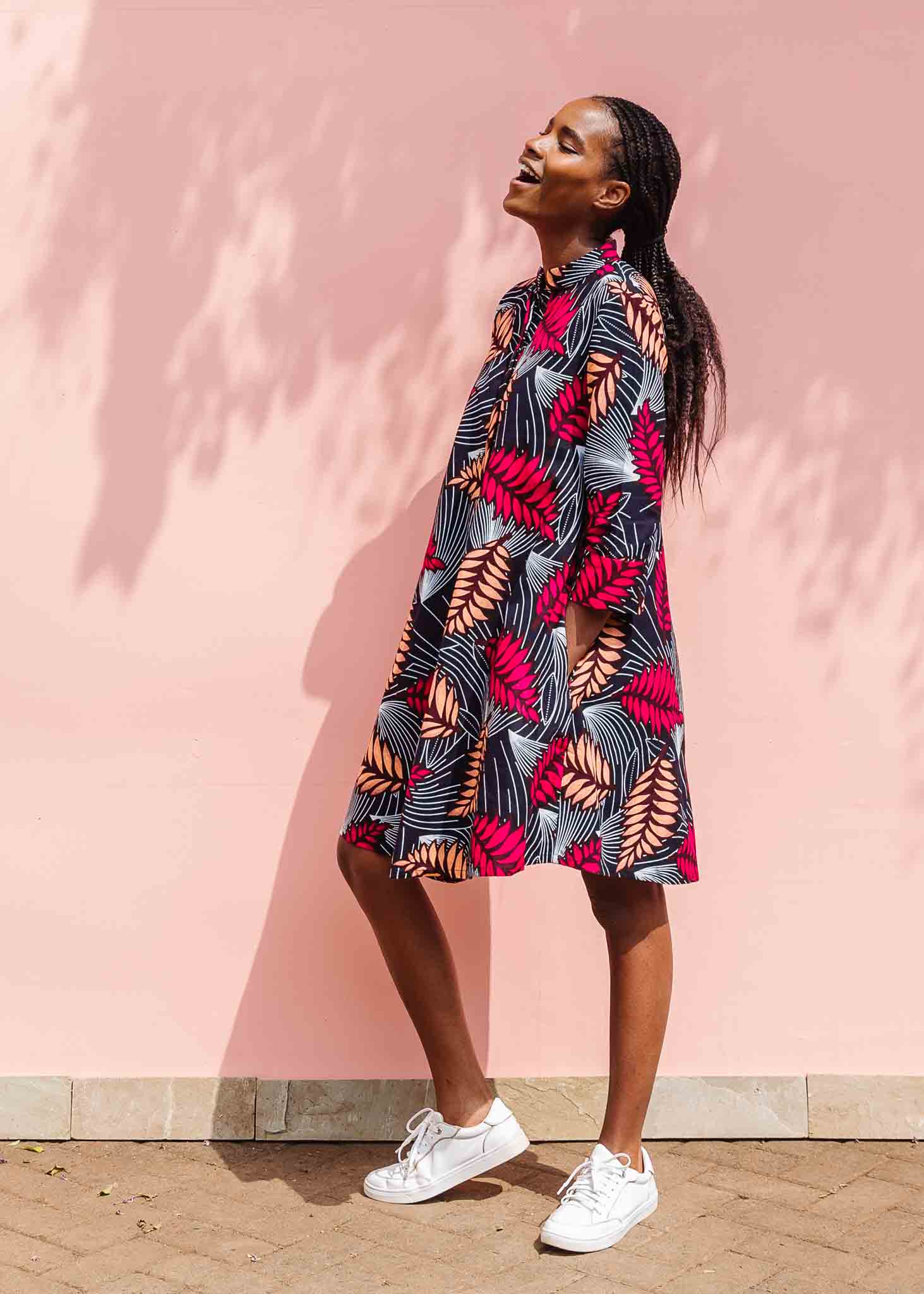 Model wearing a navy dress with red and peach feather print.