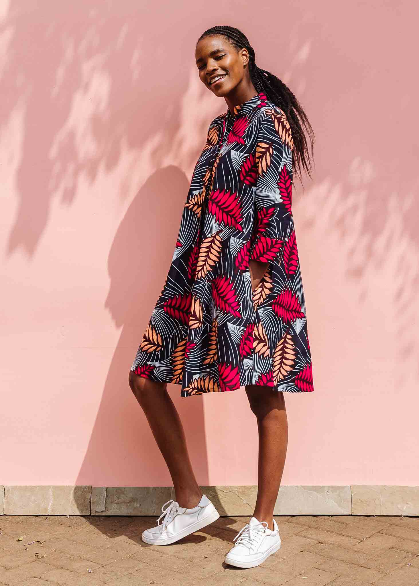 Model wearing a navy dress with red and peach feather print.