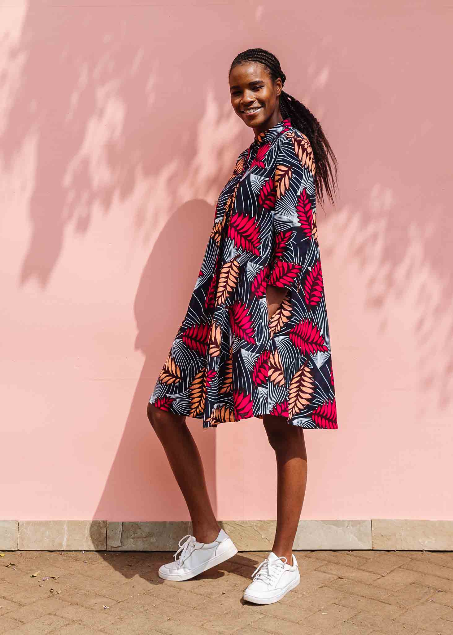 Model wearing a navy dress with red and peach feather print.